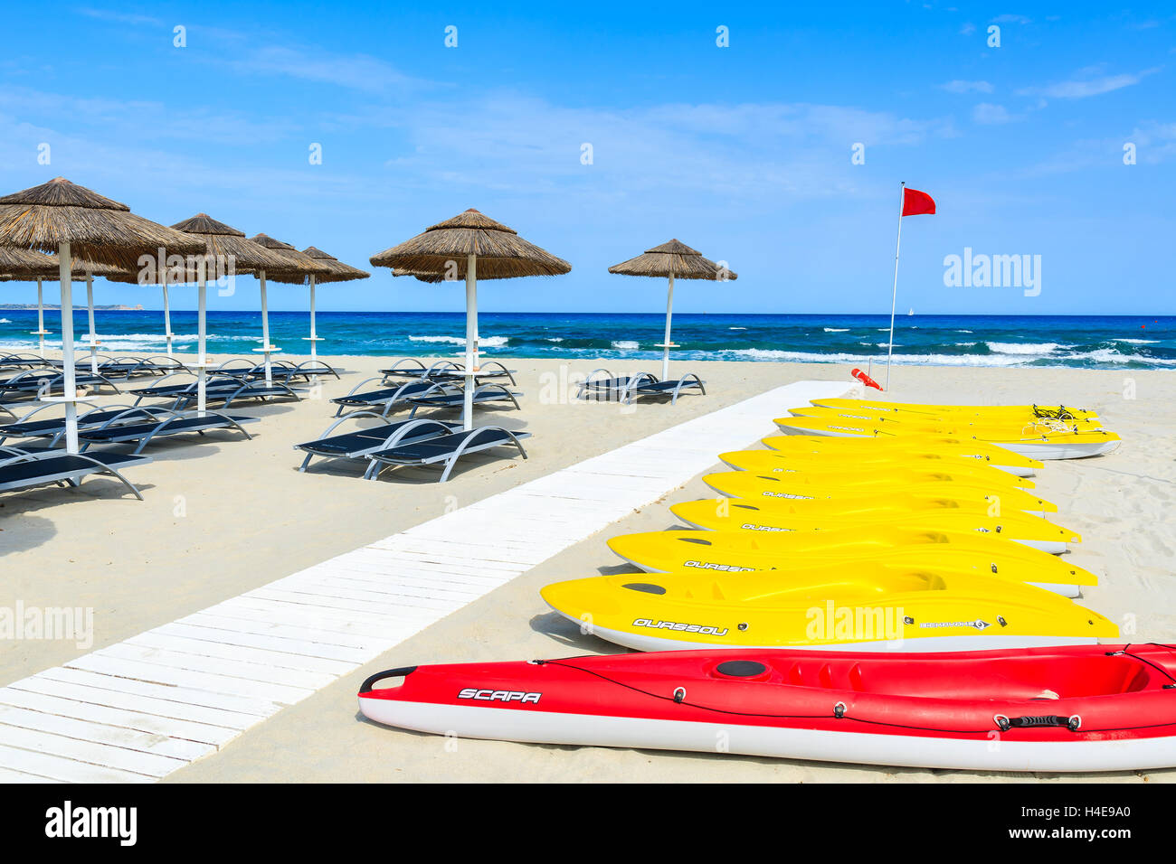 PORTO GIUNCO BEACH, SARDINIA - MAY 25, 2014: yellow kayaks and umbrellas with sunchairs on Porto Giunco beach, Sardinia island, Italy. South of the island has most beautiful beaches in Europe. Stock Photo