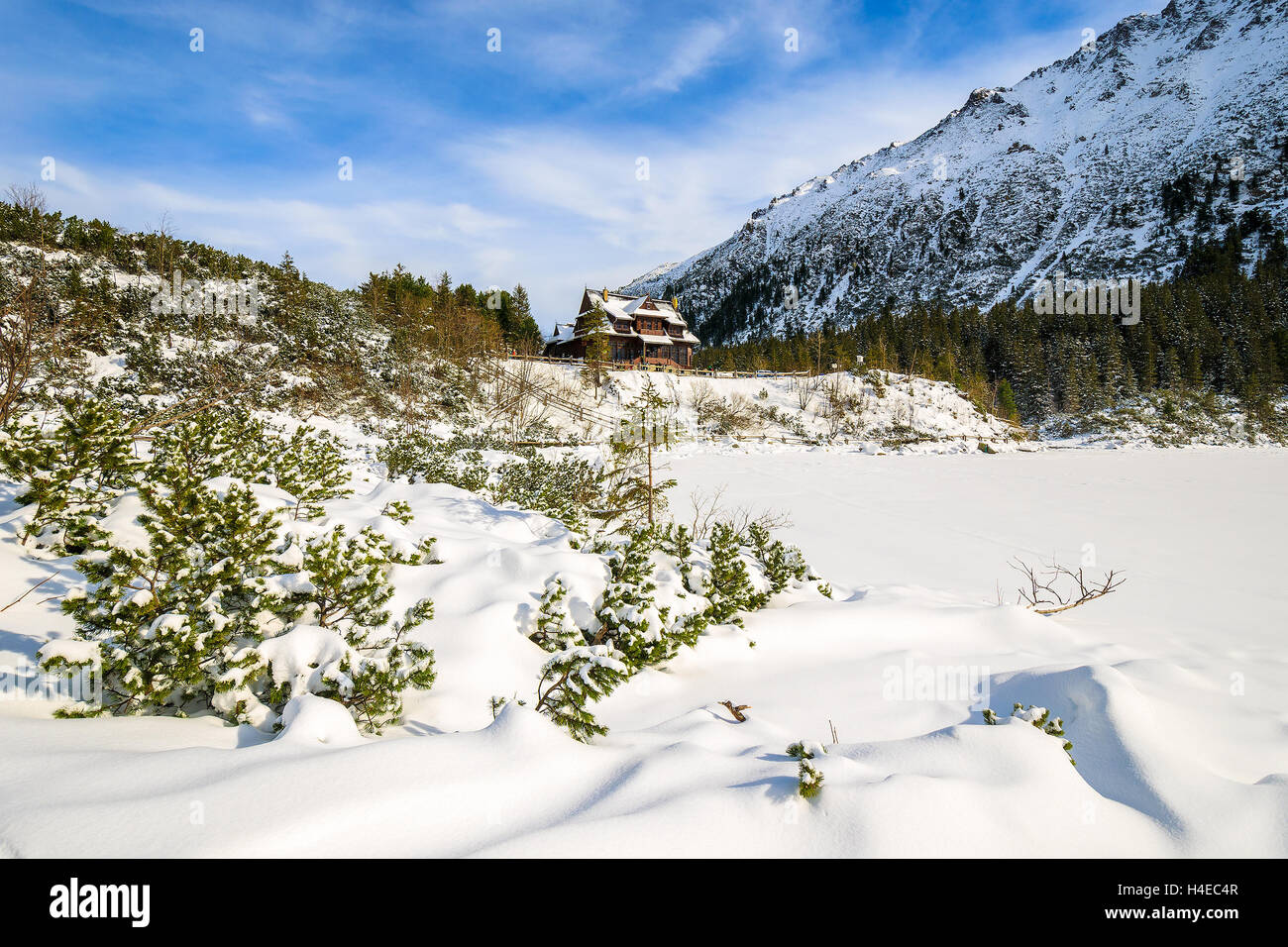 Frozen Morskie Oko lake covered with fresh snow and mountain refuge in distance, Tatra Mountains, Poland Stock Photo