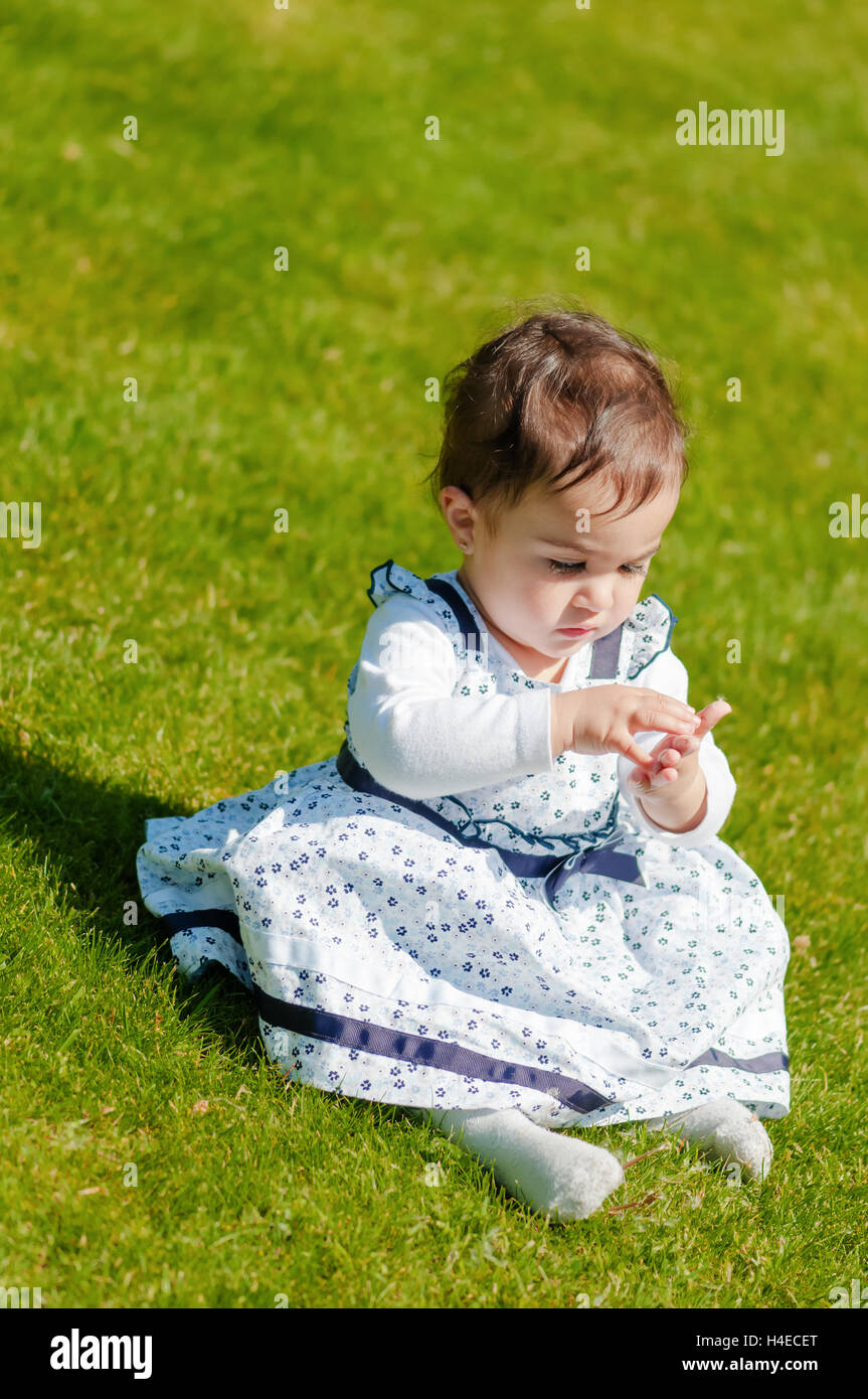 Cute chubby toddler looking at dandelion seeds curiously exploring nature outdoors in the park Stock Photo
