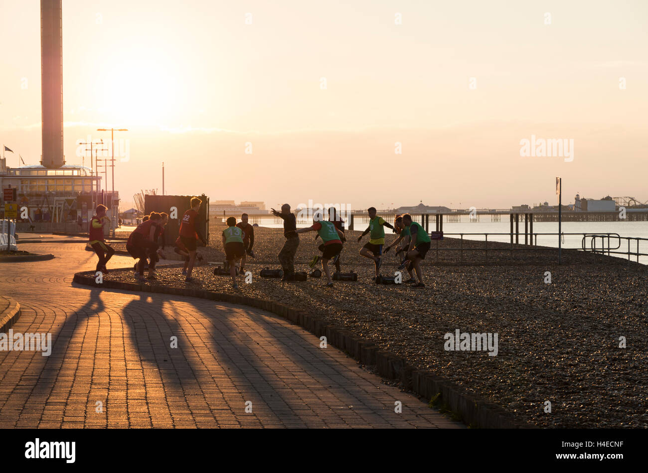 Group of men and women doing a Military Fitness bootcamp exercise workout on the beachfront at sunrise, Brighton & Hove UK Stock Photo