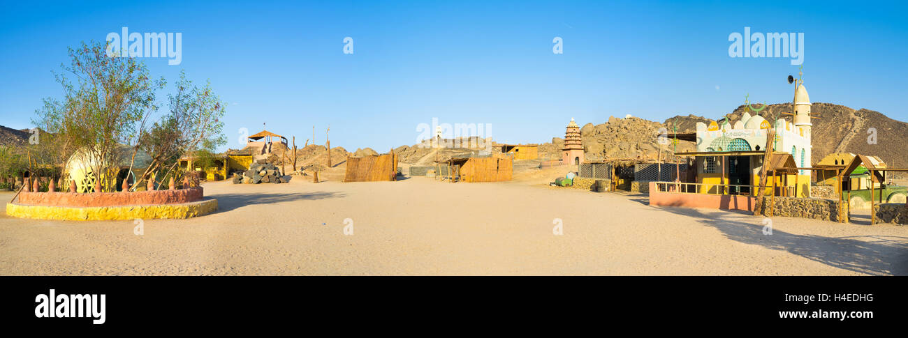 Panorama of the Bedouin village with the old mosque, corral for camels and the draw-well, surrounded by bushes, Sahara, Egypt. Stock Photo