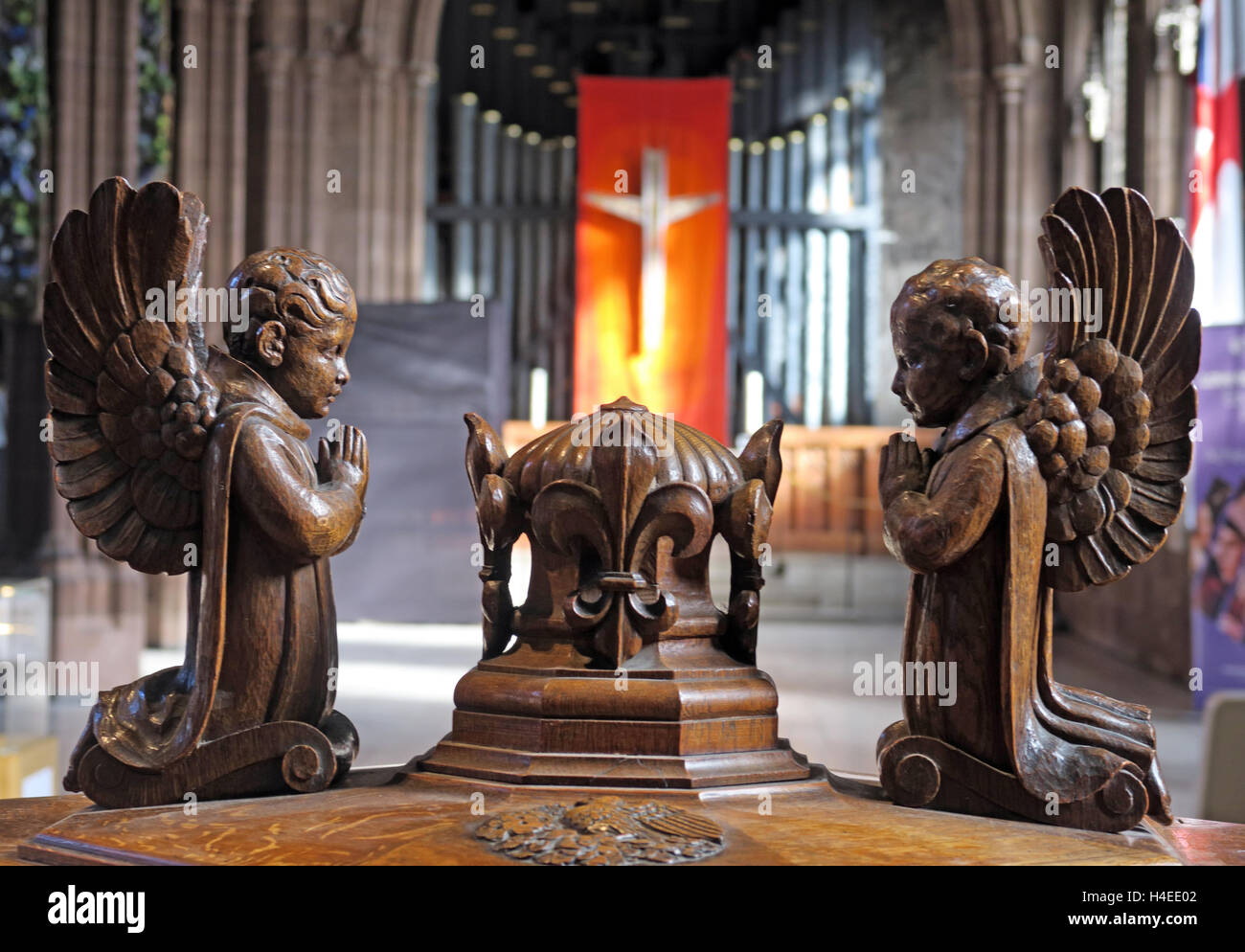 Crucifix and organ pipes behind font angels,Manchester cathedral,England,UK Stock Photo