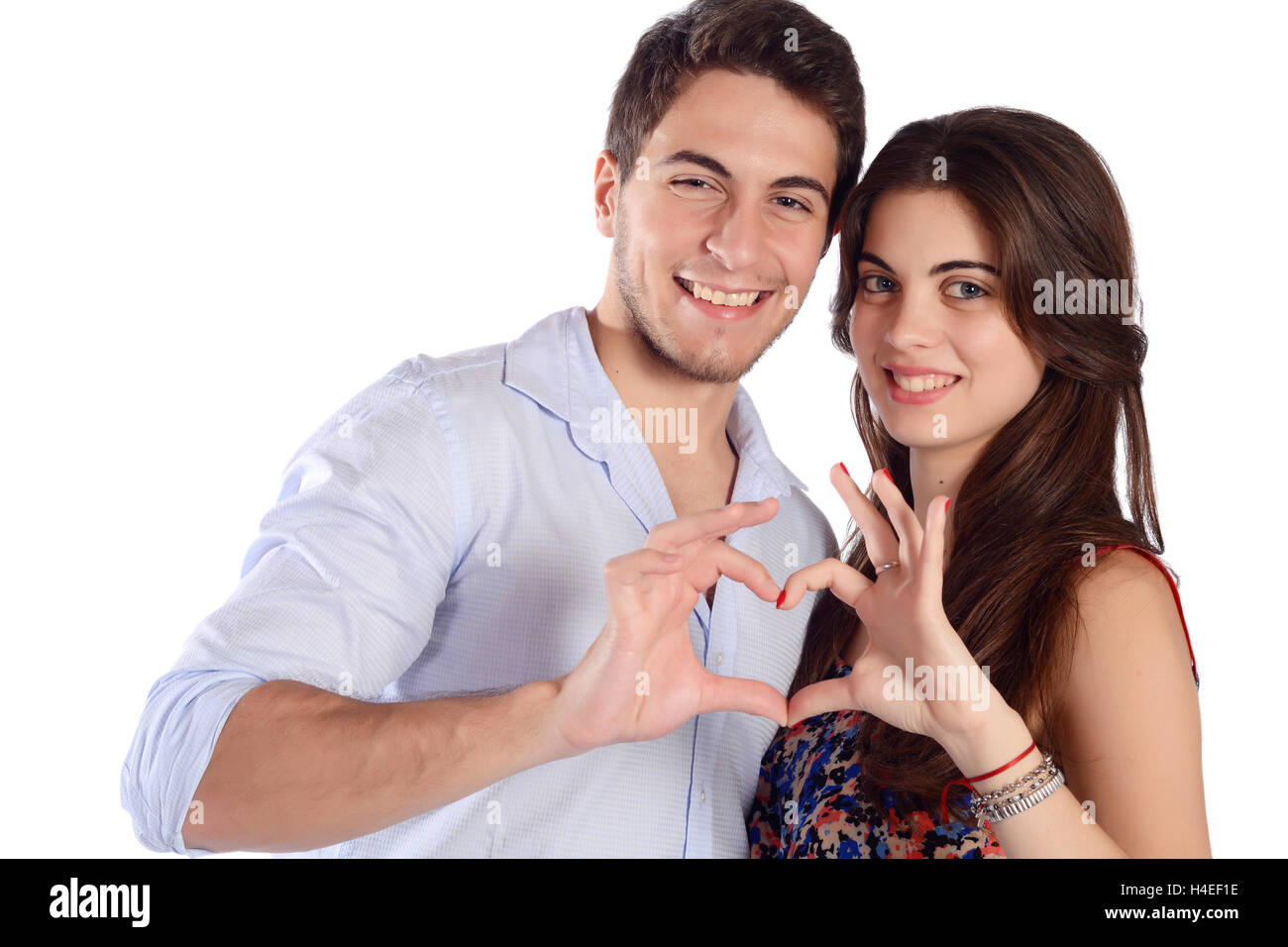 Portrait of a young beautiful couple making heart shape with hands ...