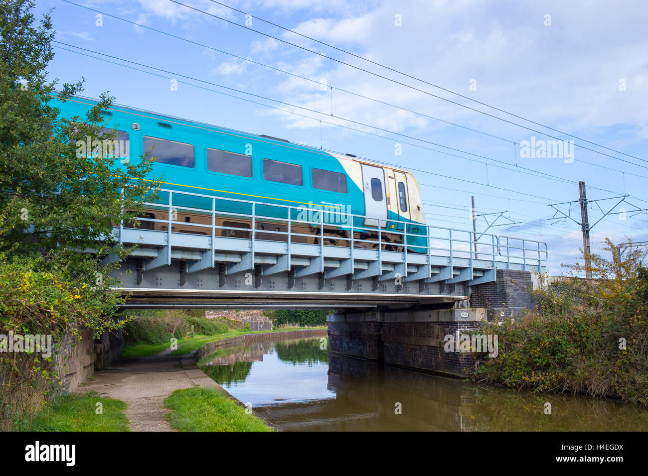 Passing train on railway bridge over Trent and Mersey canal in Cheshire UK Stock Photo