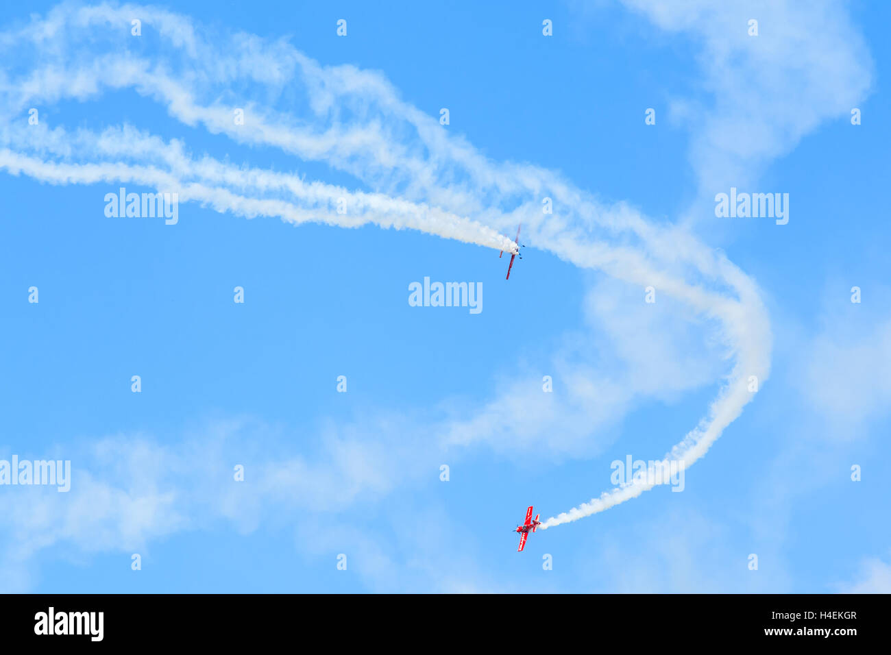 KRAKOW MUSEUM OF AVIATION, POLAND - JUL 27, 2014: two red acrobatic planes flying on blue sky at airshow in Krakow, Poland. In summer often airshows take place here. Stock Photo