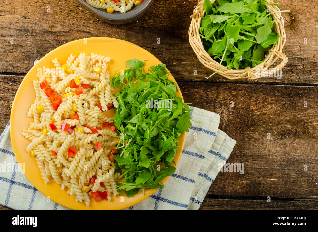 Pasta salad with vegetable and arugula salad with olive oil, wood table