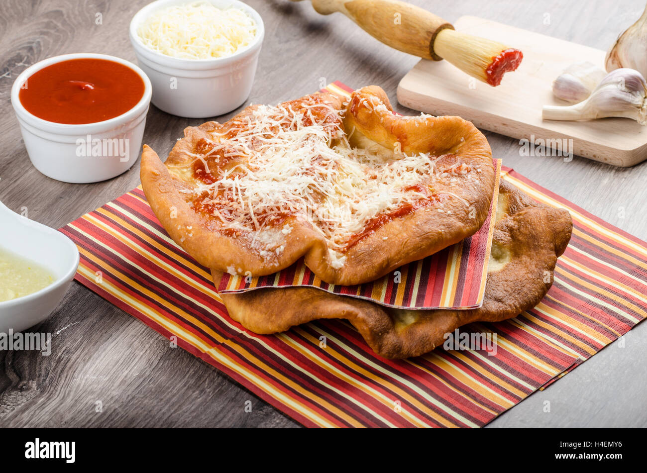 Traditional carnival fast food specialty, fried yeast dough with cheese, ketchup and garlic Stock Photo