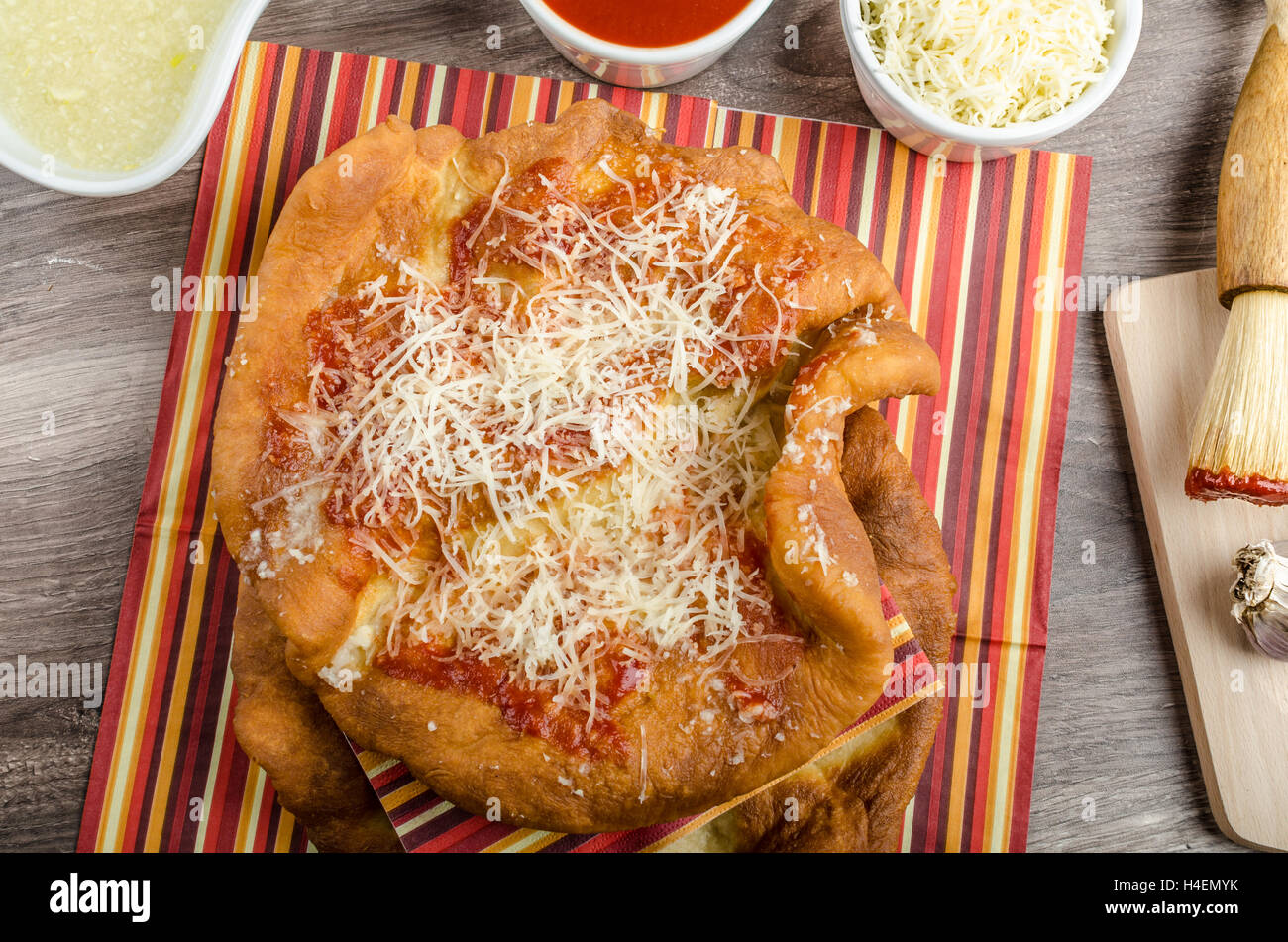 Traditional carnival fast food specialty, fried yeast dough with cheese, ketchup and garlic Stock Photo