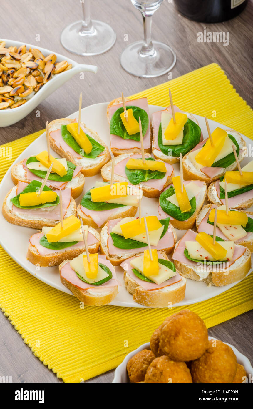 New Year's Eve meal - canapes with ham, cheese and spinach leaves, spicy  cheese balls (Aigrettes), onion rings, roasted nuts with thyme and olive  oil Stock Photo - Alamy