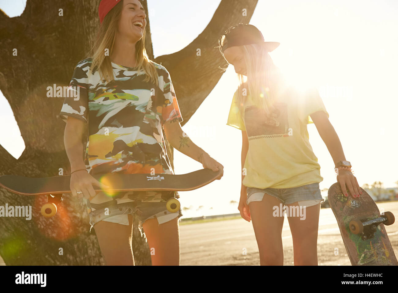 Two russian skater girls are laughing happy with skateboards on sunset Stock Photo