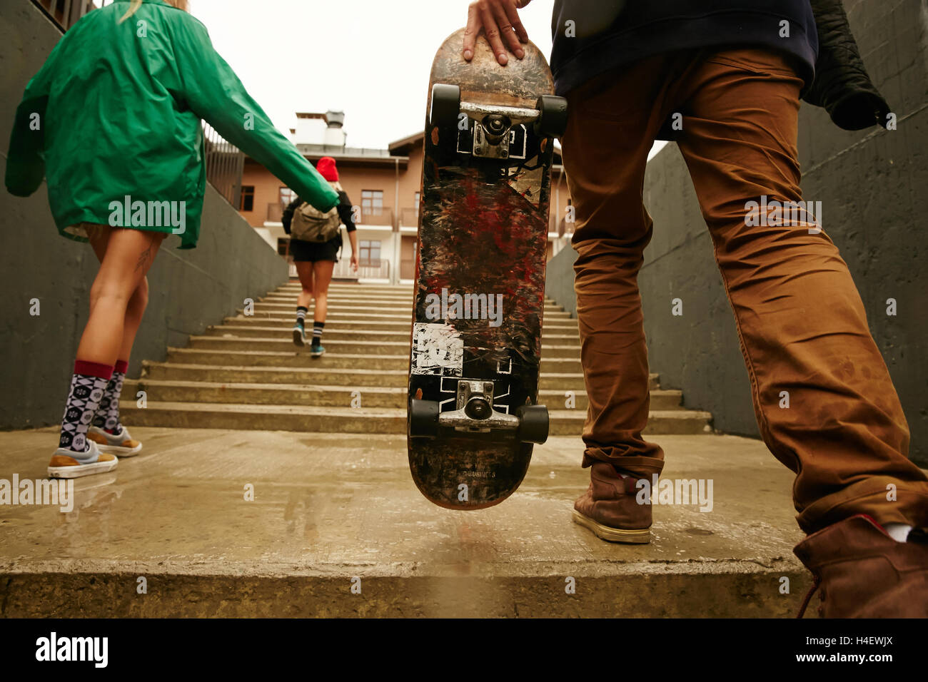 Guys are going up the stairs with a skateboard in rainy weather in Sochi Riders Lodge Stock Photo