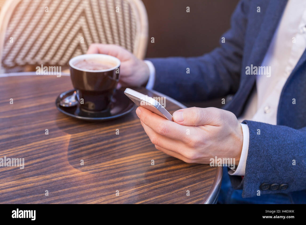 Young adult using mobile phone on restaurant terrace with coffee Stock Photo