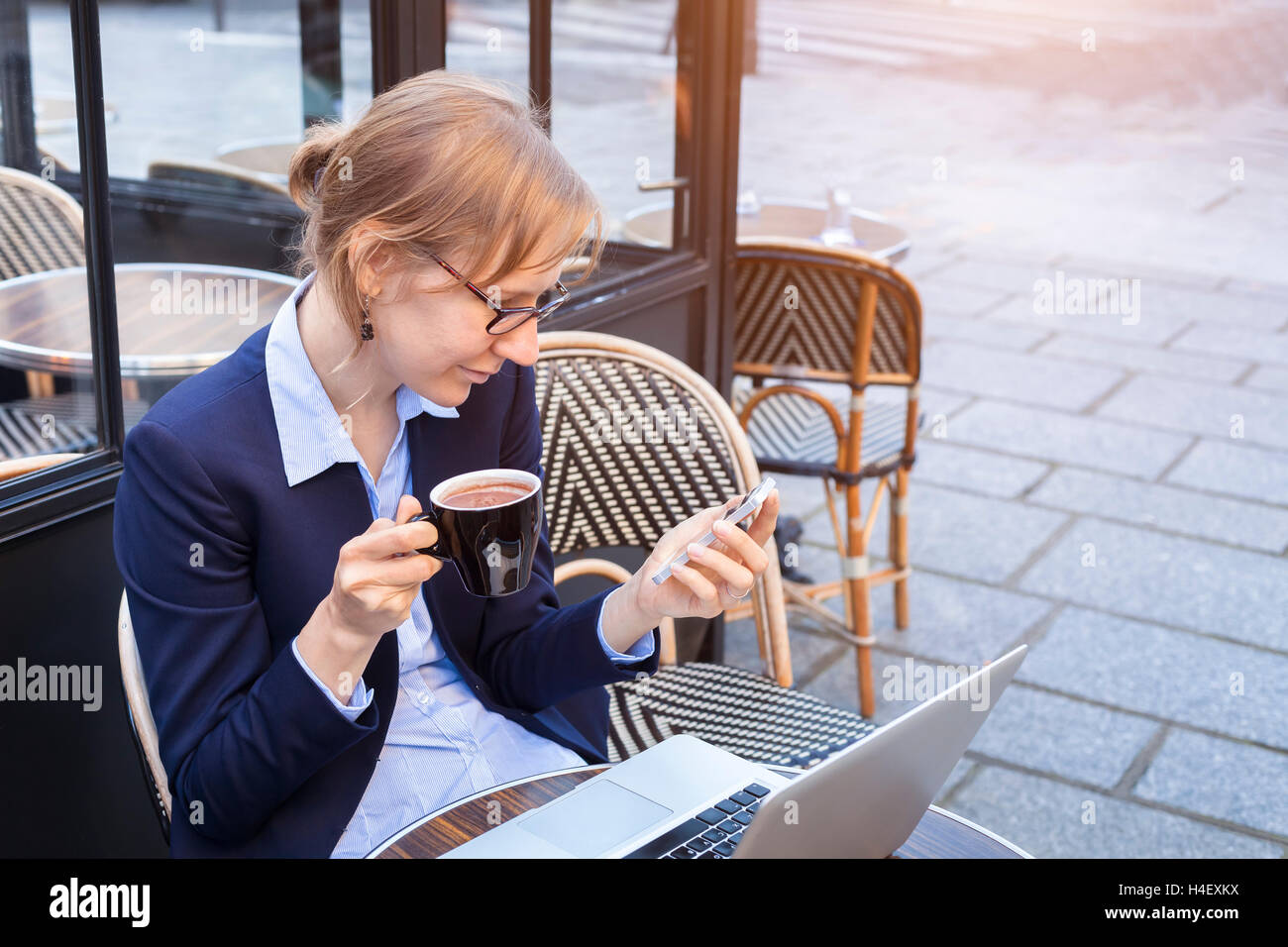 Young happy business woman using smartphone and laptop at lunch on terrace Stock Photo