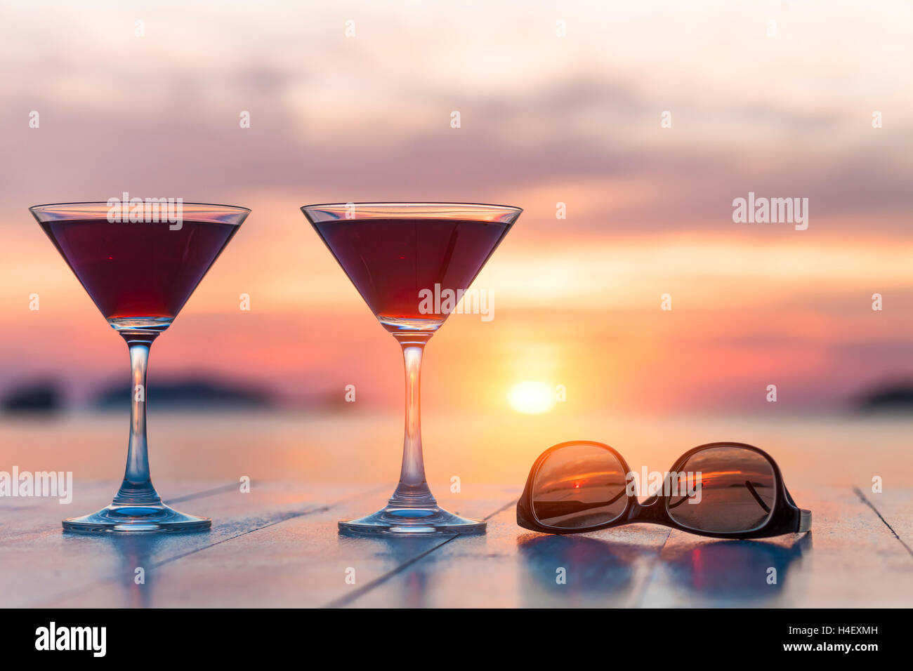 Two cocktails and sunglasses at a beach restaurant, honeymoon, sunset Stock Photo