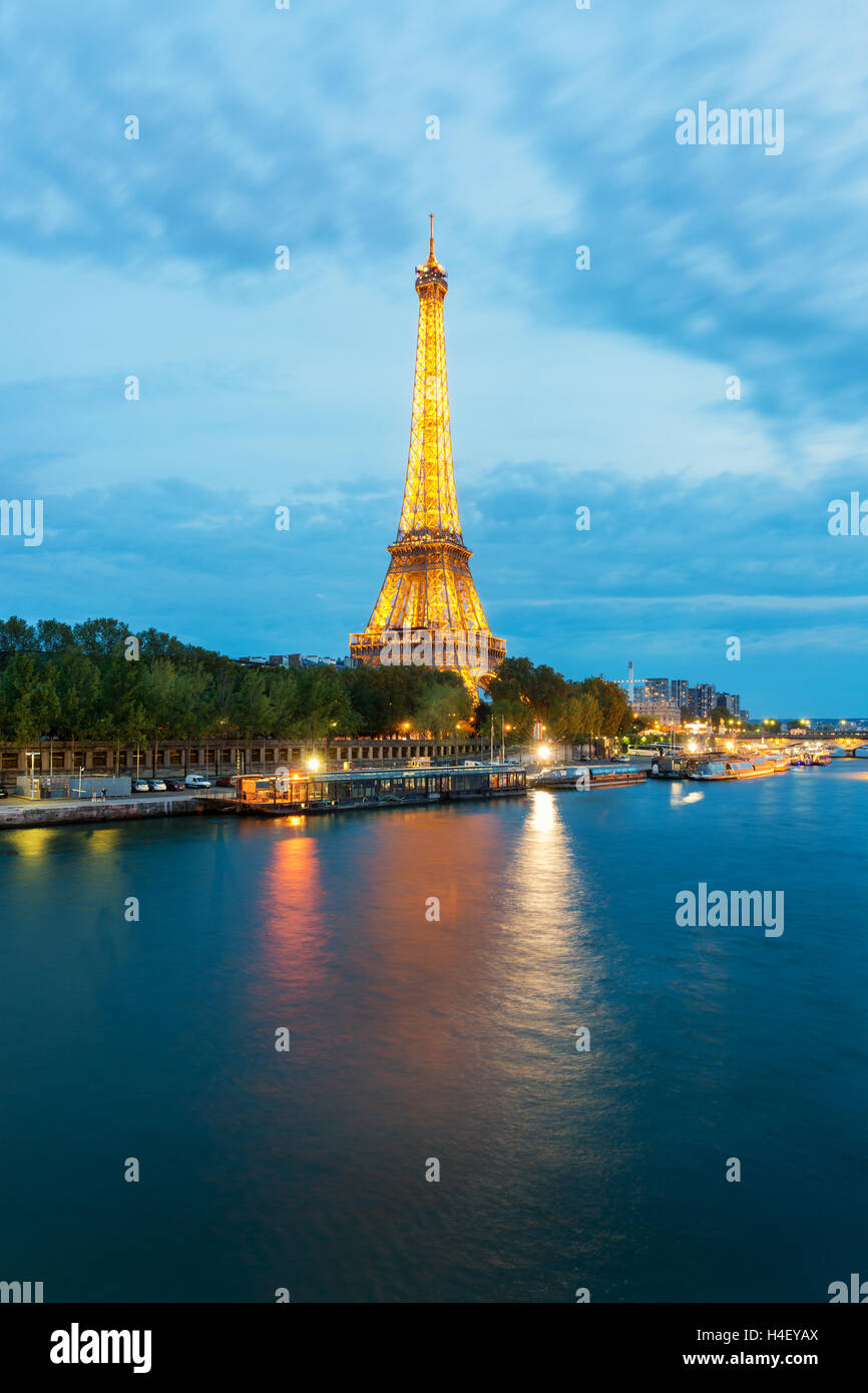 Beautiful Paris view of illuminated Eiffel tower along Seine river at dusk, Paris, France. Stock Photo