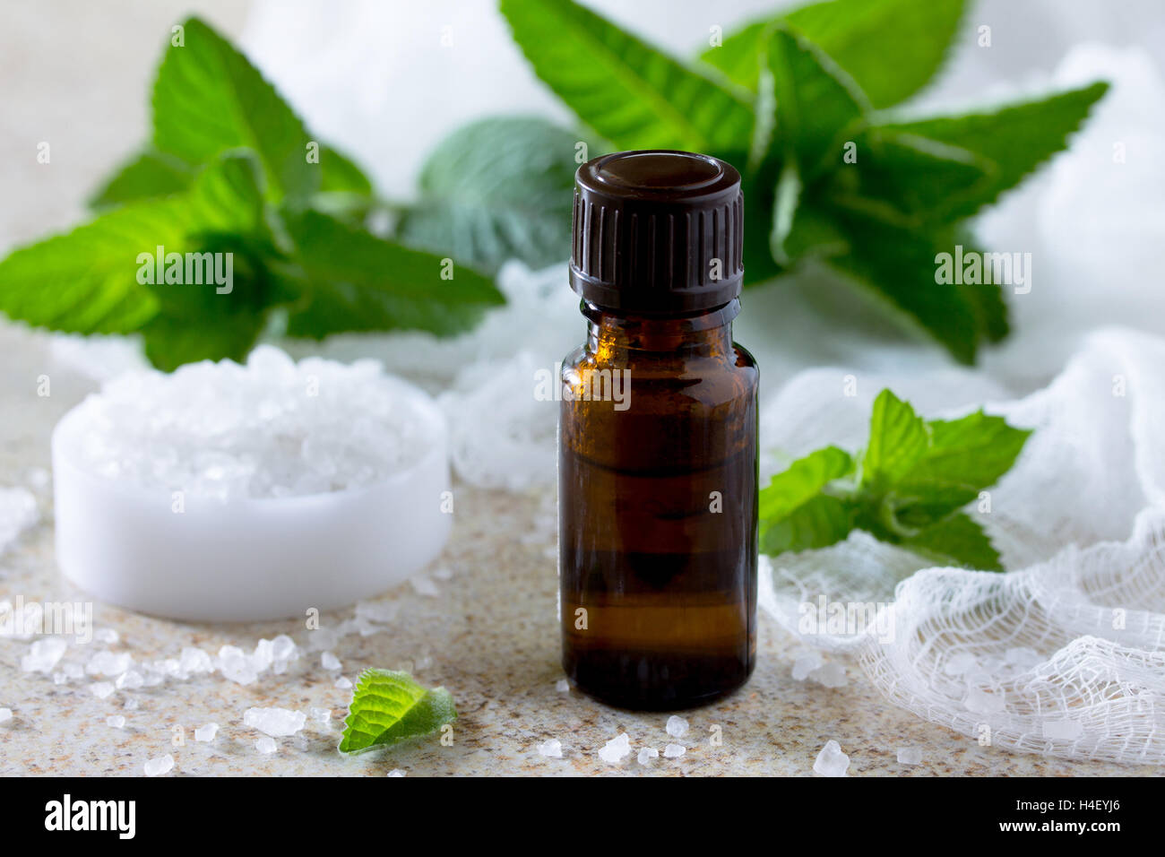bottle of peppermint essential oil for aromatherapy on a brown stone background. Stock Photo