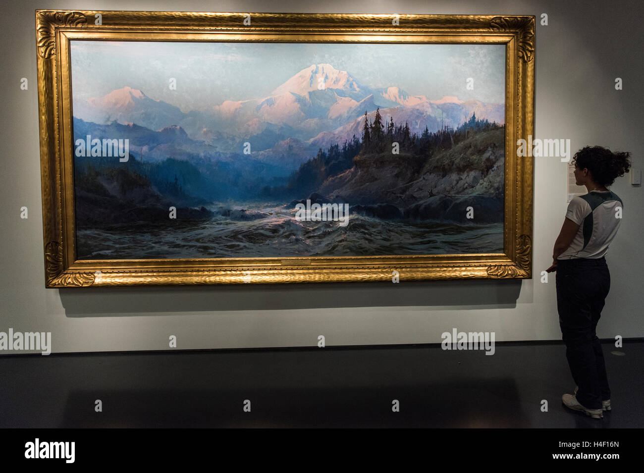 Tourist looking at painting of Denali mountains by Alaska painter Sydney Laurence, Alaska Native Heritage Centre, Anchorage Stock Photo