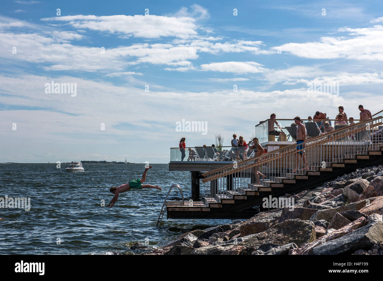 People jumping in the water from Lšyly public waterfront sauna, Hernesaari, Helsinki, Finland Stock Photo
