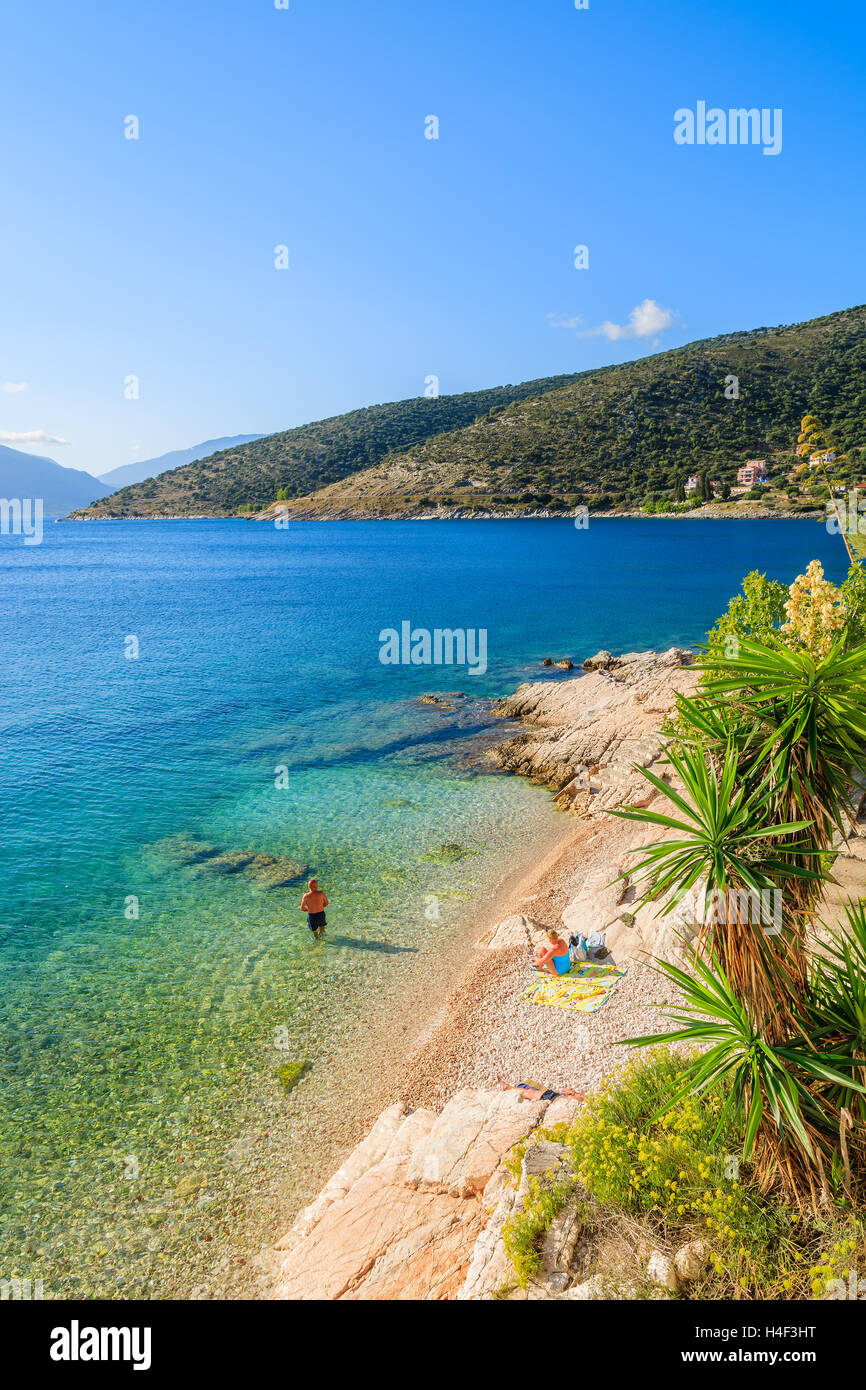 Unidentified couple of people relaxing on beach on coast of Kefalonia island in Agia Efimia, Greece Stock Photo