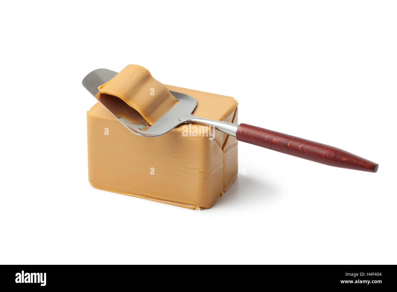 Piece of norwegian flotemysost cheese and slicer on white background