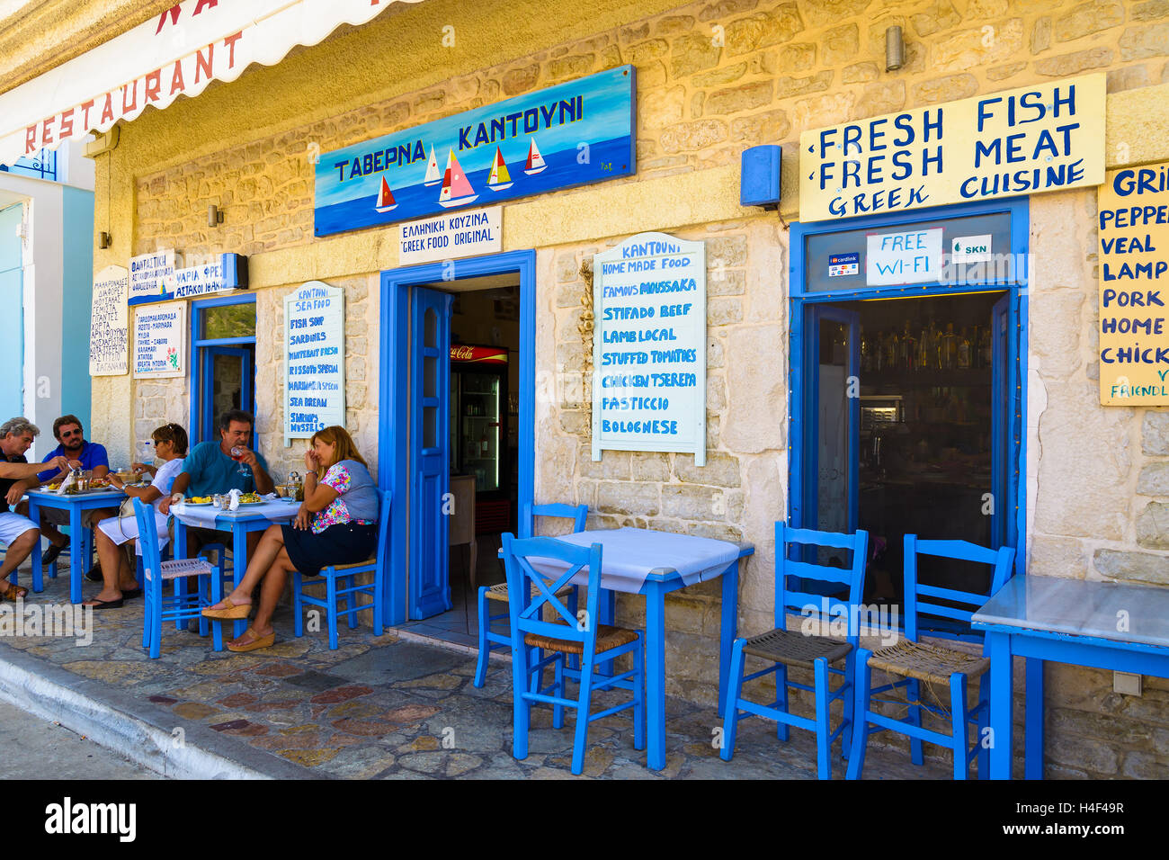 VATHY TOWN, ITHAKA ISLAND, GREECE - SEP 17, 2014: people sitting in traditional Greek restaurant in seaside town Vathy. Greece is famouse for great food served in taverns. Stock Photo