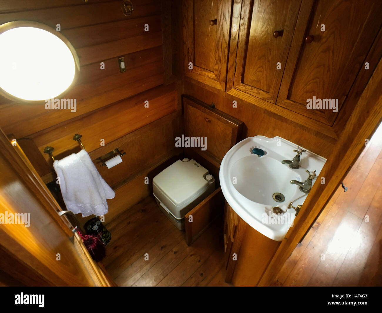 Bathroom showing toilet and washbasin on board a narrowboat with oak built cupboards Stock Photo