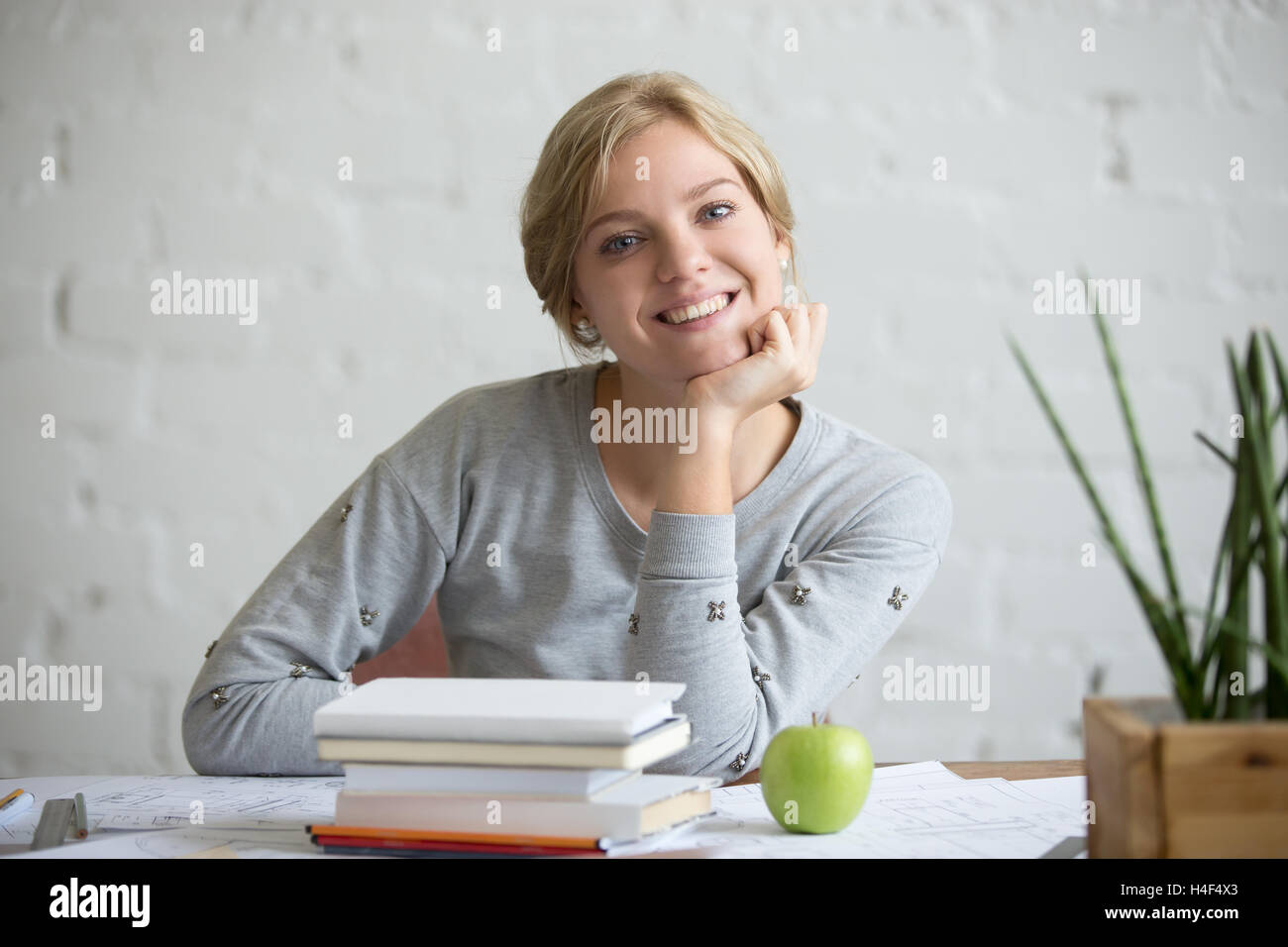 Portrait of smiling girl at desk with books and apple Stock Photo - Alamy
