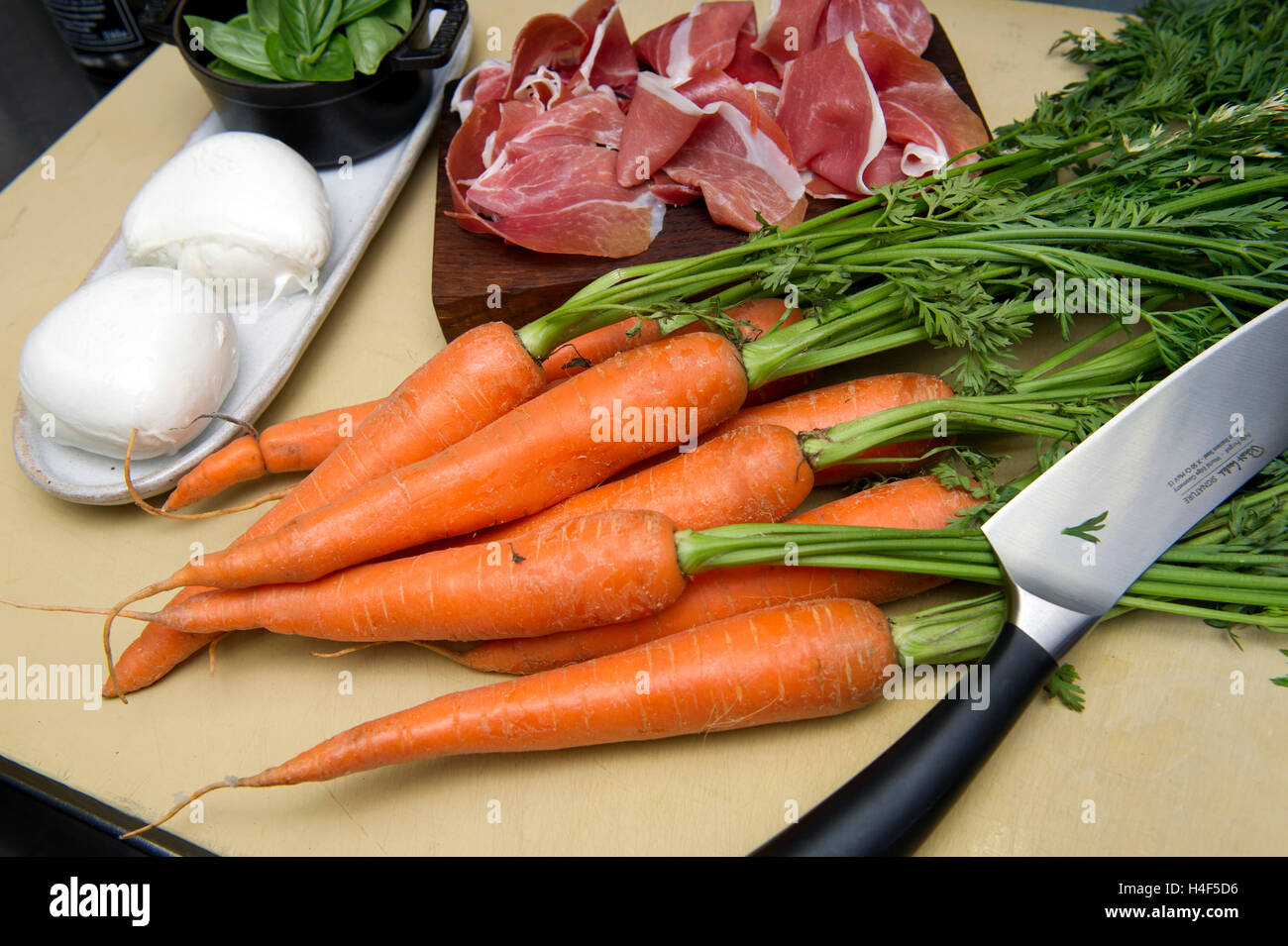 Raw carrots with a knife and carrots cooking in a shallow frying pan. a