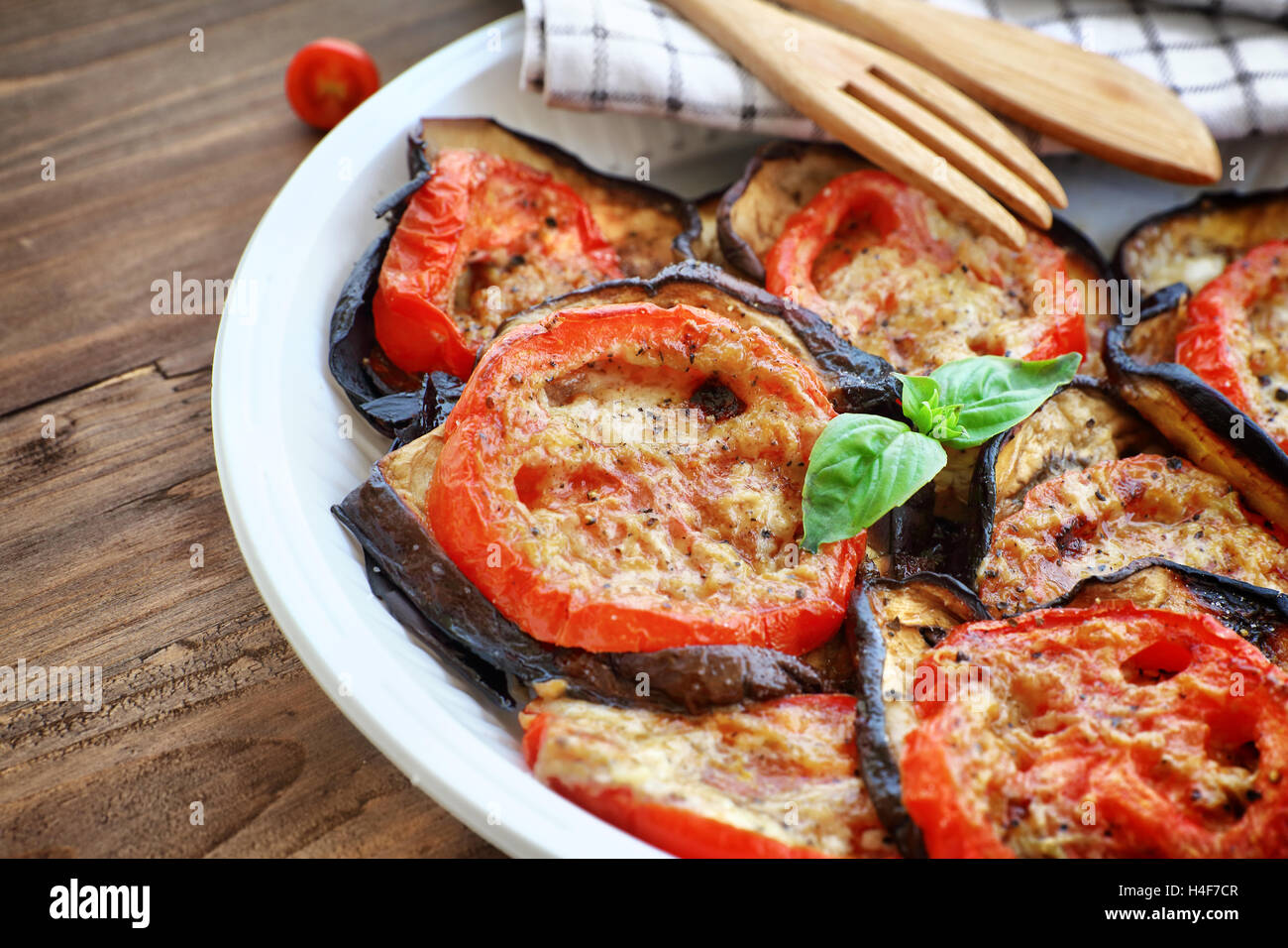 Tasty pizza topping, roasted aubergine with tomatoes and basil on the plate on the wooden table, delicious homemade food Stock Photo
