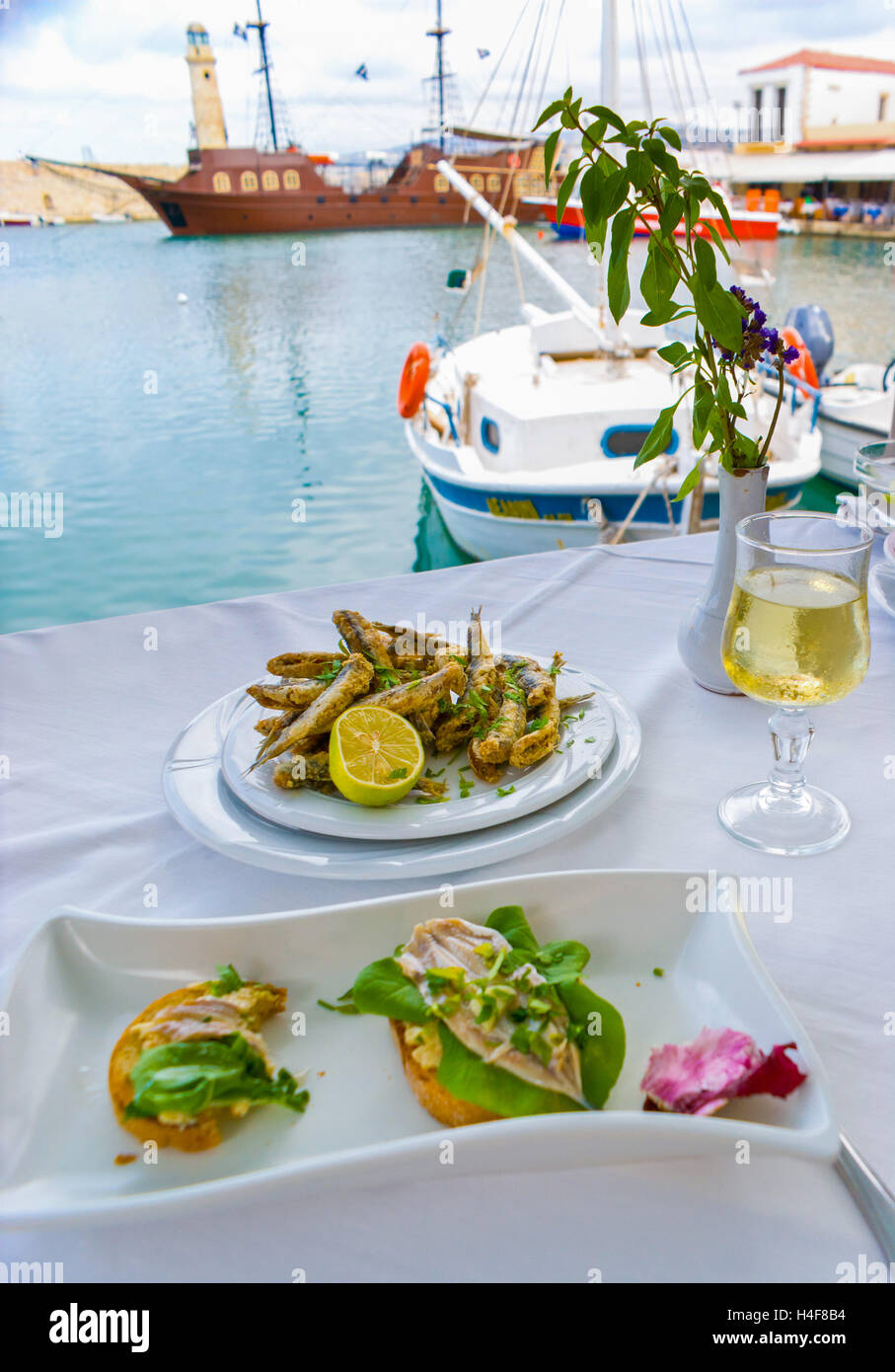 The romantic supper in the small cafe with local cuisine, consisting of seafood, Old Venetian Port of Rethymno, Crete, Greece. Stock Photo