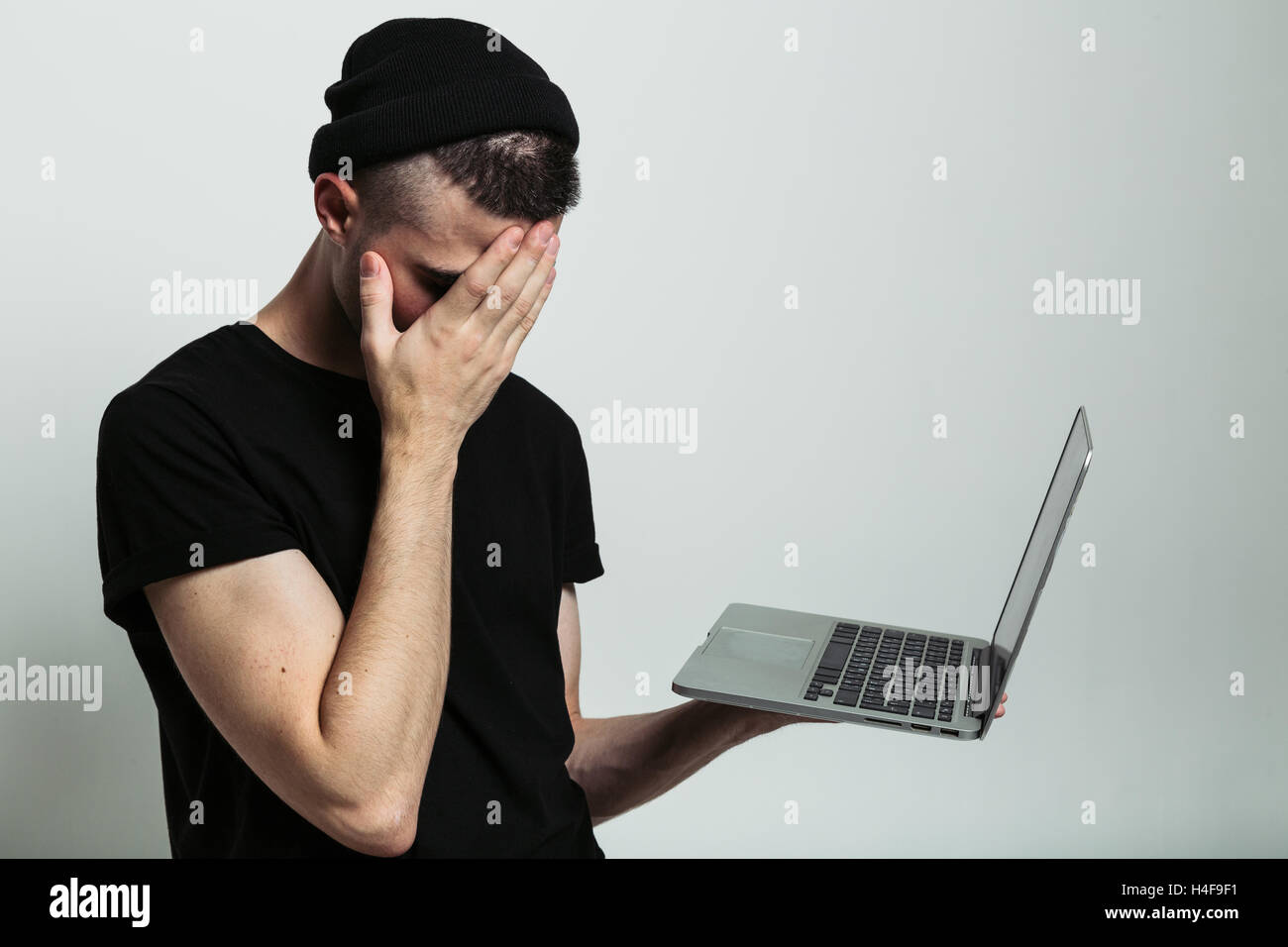 Close up view of man with laptop and facepalm. Stock Photo