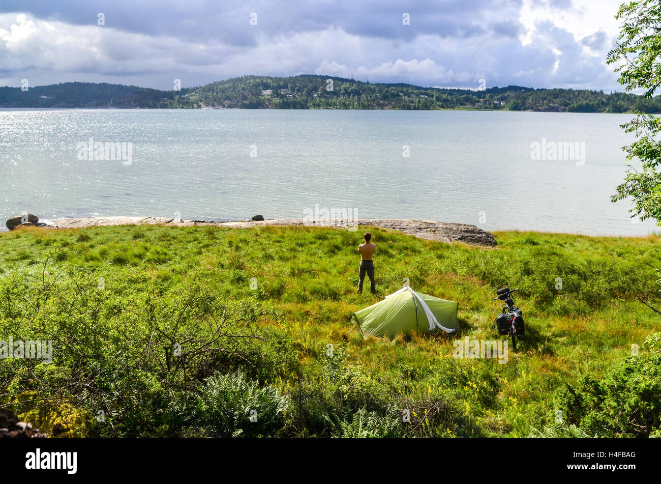Man standing near tent after camping in Sweden (Orust) Stock Photo