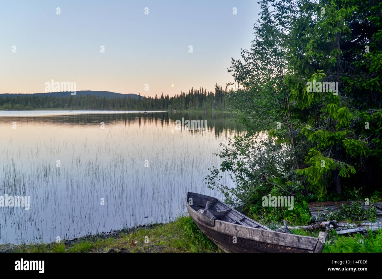 Old barge by a lake in a forest of Sweden, with a full moon Stock Photo