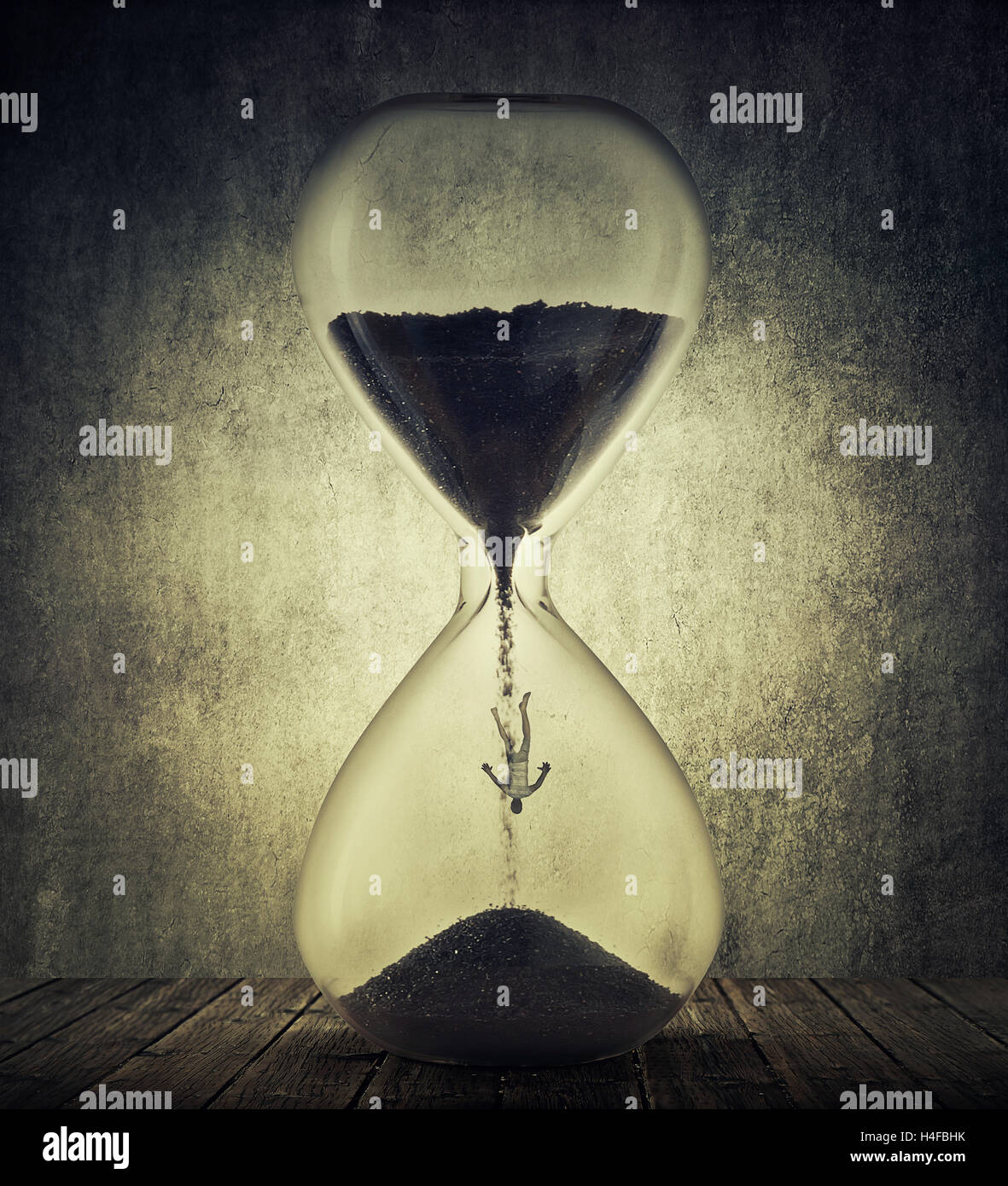 Young man falling inside a hourglass with black sand. Time management productivity concept. Human aging process, and age related Stock Photo