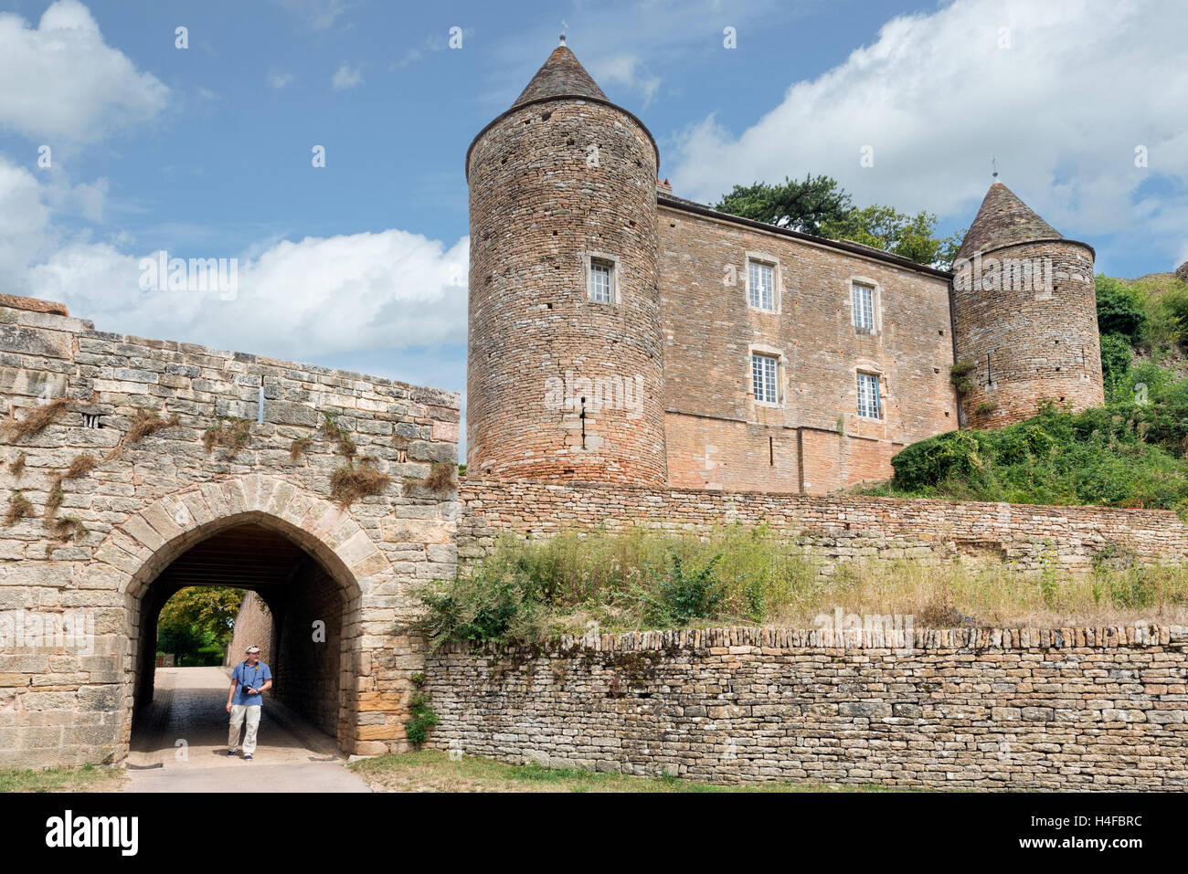 A visitor walking through the tunnel entrance to Chateau de Brancion & historic village in Saone et Loire, Burgundy, France Stock Photo