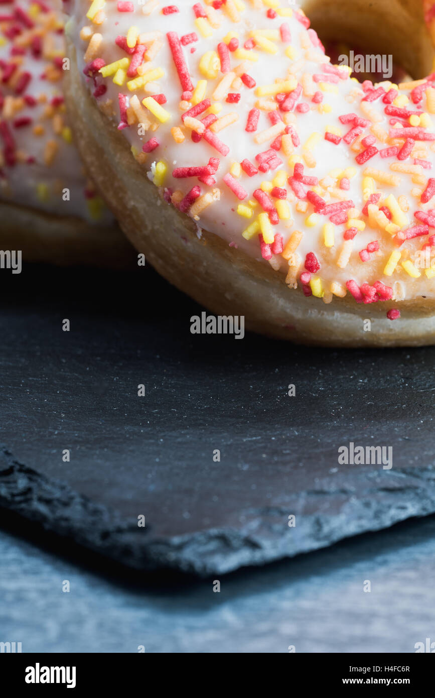 A portrait shot of iced donuts on a slate. Stock Photo