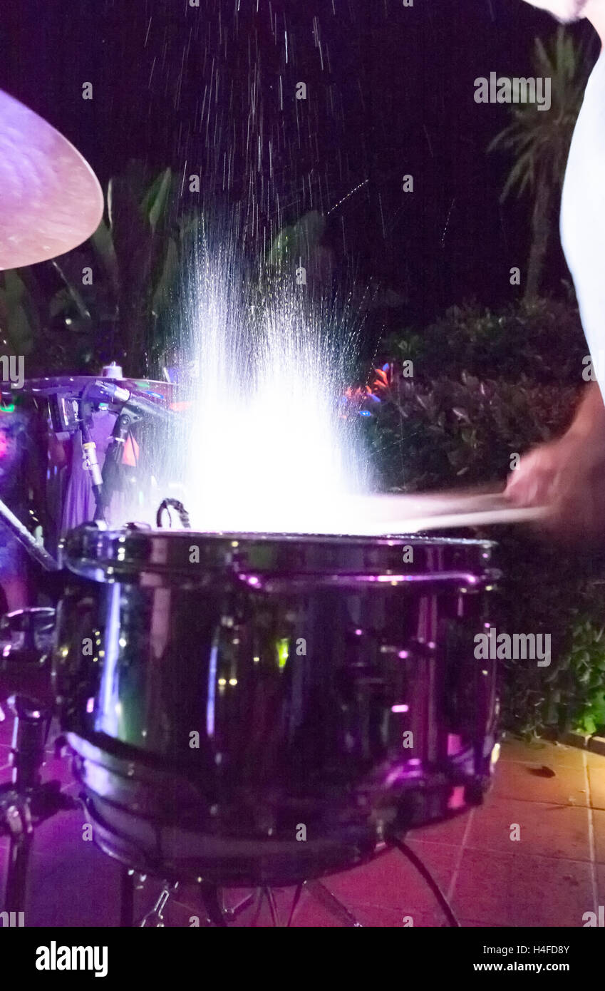 Drummer beating and splashing drums at night show. Slow motion shot Stock Photo