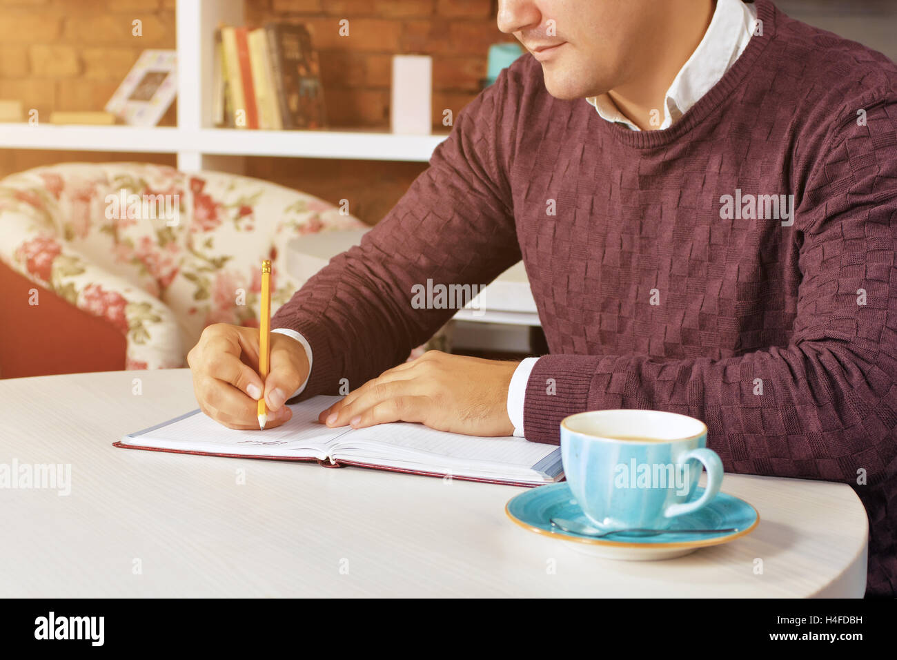 Man holding pencil and writing on a paper in the diary Stock Photo - Alamy