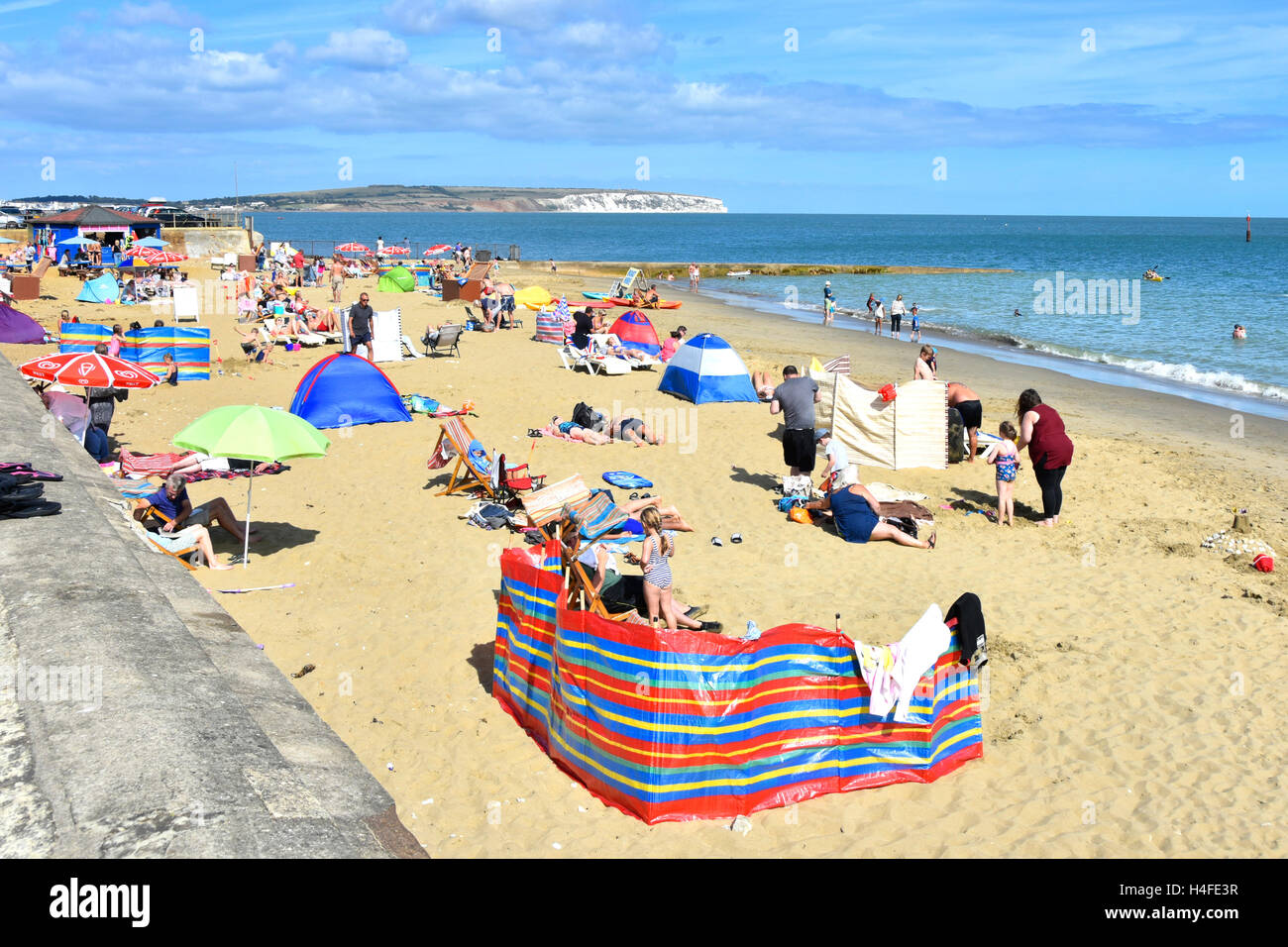 Busy sandy UK English summer holiday beach at Shanklin on the Isle of White hot summers day with white Culver Cliff distant along coastline Stock Photo