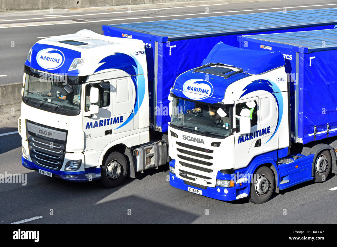 Close up two lorry cabs & trailer with driver from Maritime logistics company hgv truck drivers stuck in cab in traffic jam on m25 England UK motorway Stock Photo