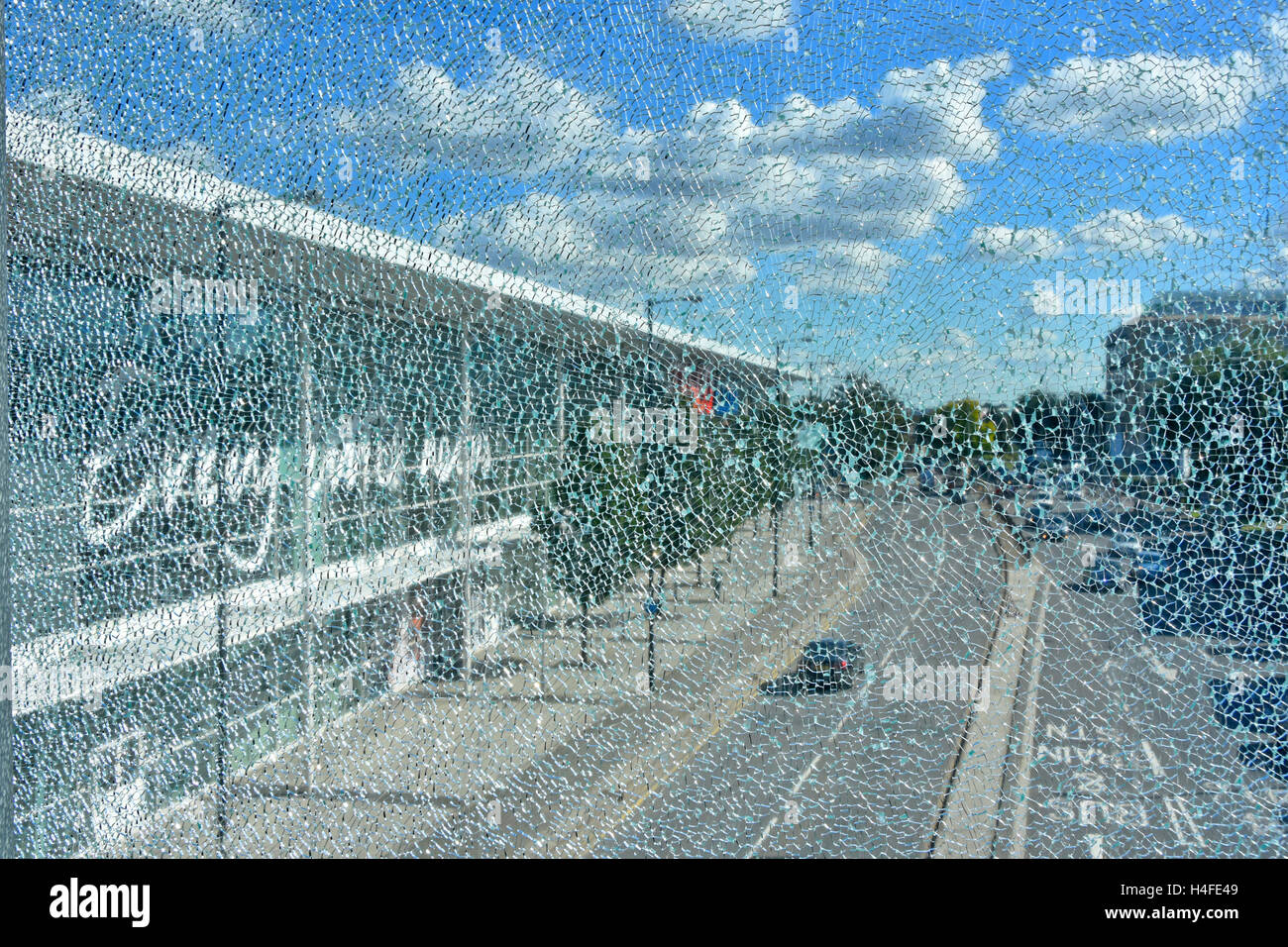 Shattered concept vision of a main road & Tesco Store in Slough Berkshire UK as seen through a crazed broken glass window pane on a blue sky sunny day Stock Photo