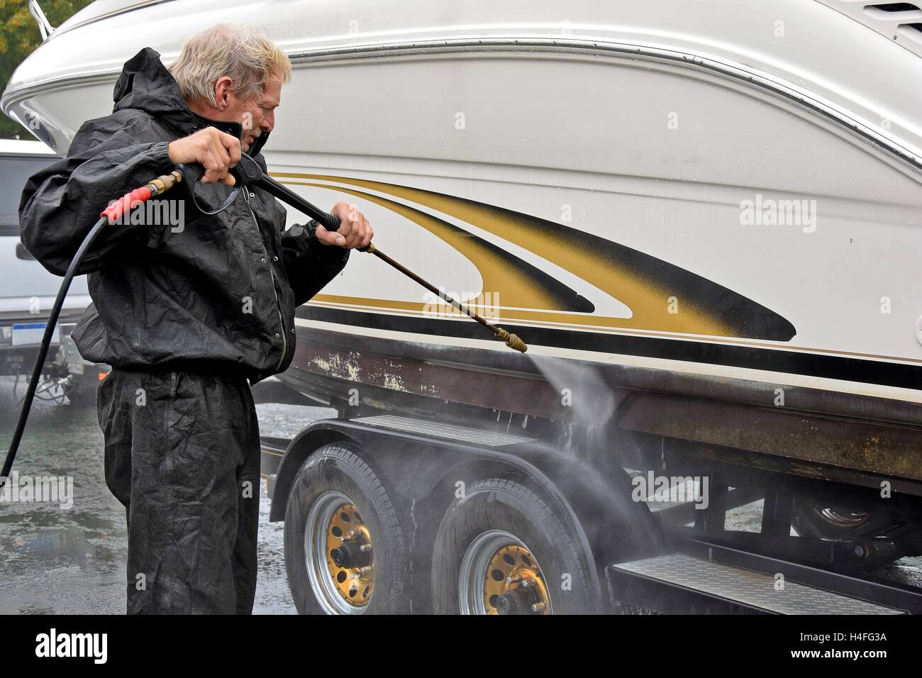 Caucasian man cleaning boat with pressure washer Stock Photo