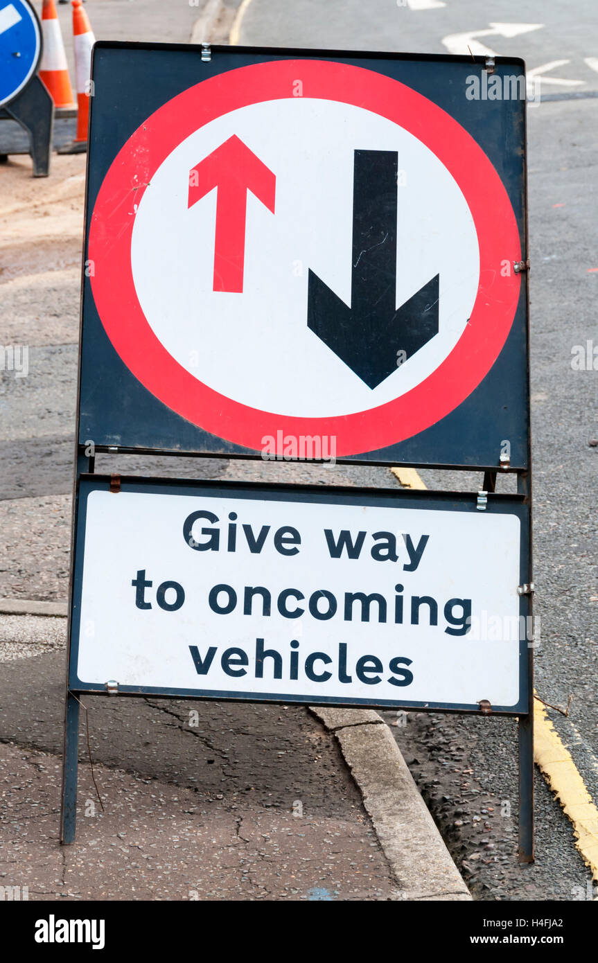 A temporary road sign warns driver to give way to oncoming vehicles. Stock Photo