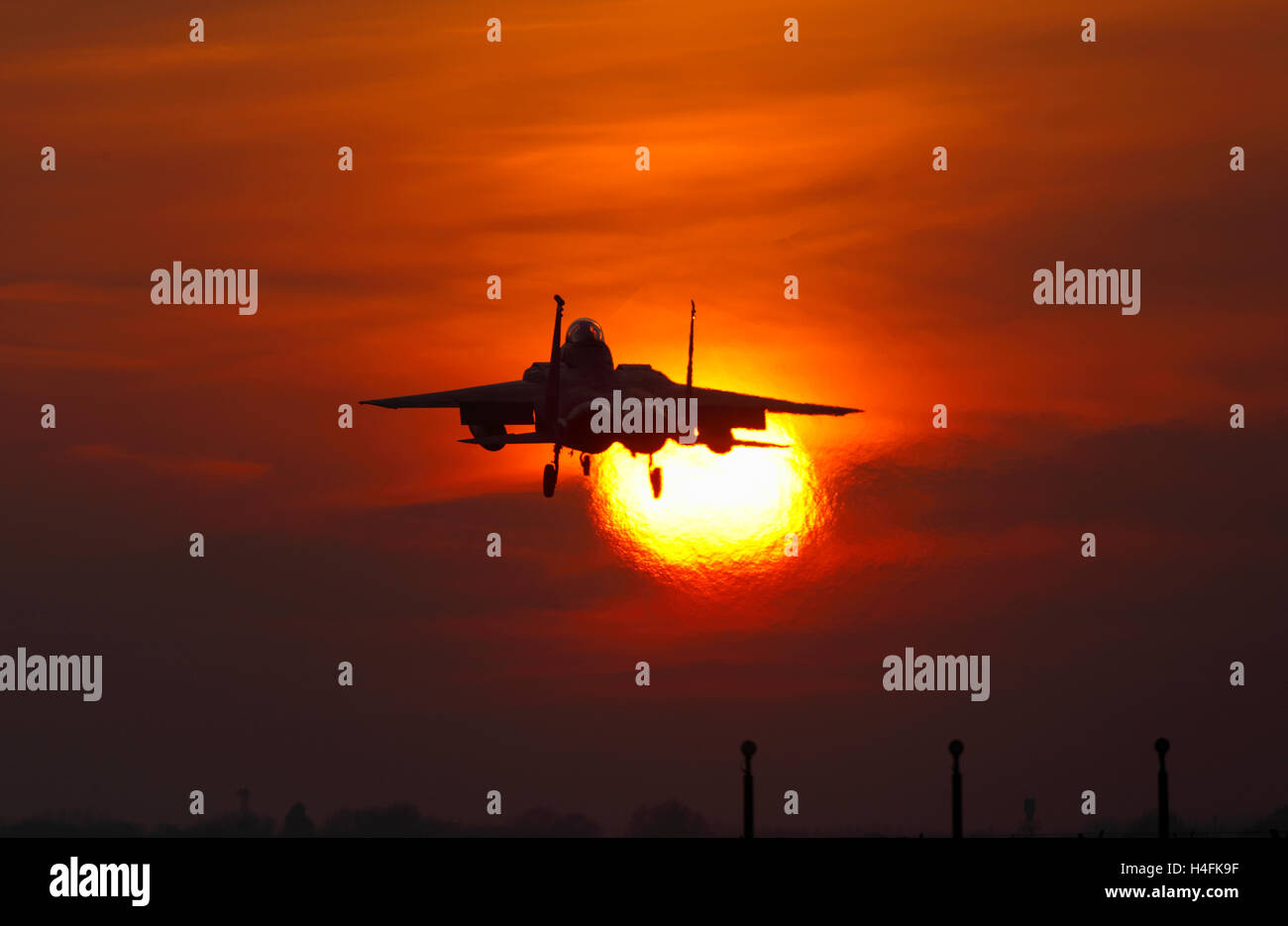 USAF F-15E Eagle passing across the setting Sun at RAF Lakenheath Stock Photo