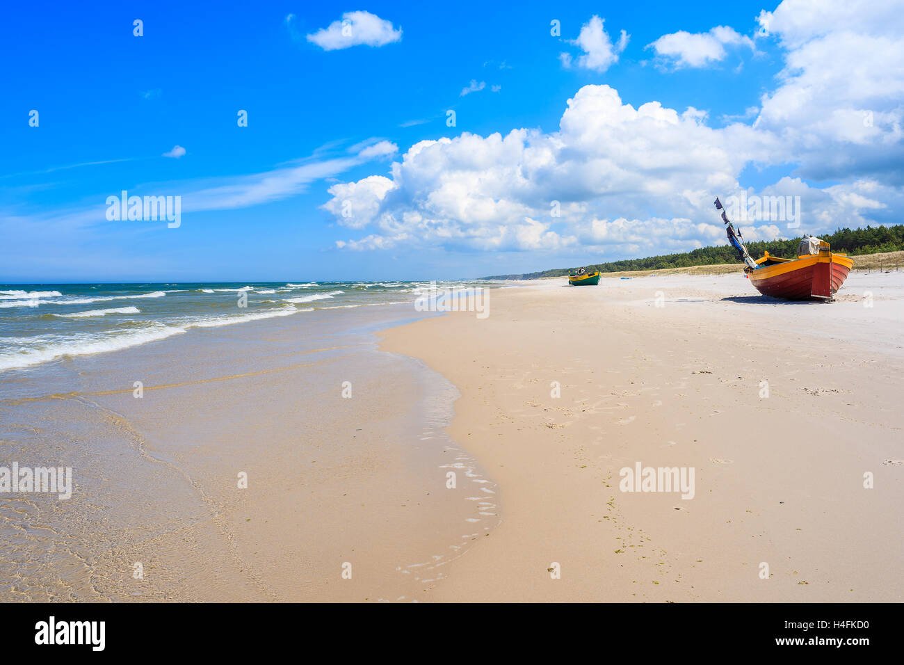 Sandy Baltic Sea beach and fishing boats on shore in background, Poland Stock Photo