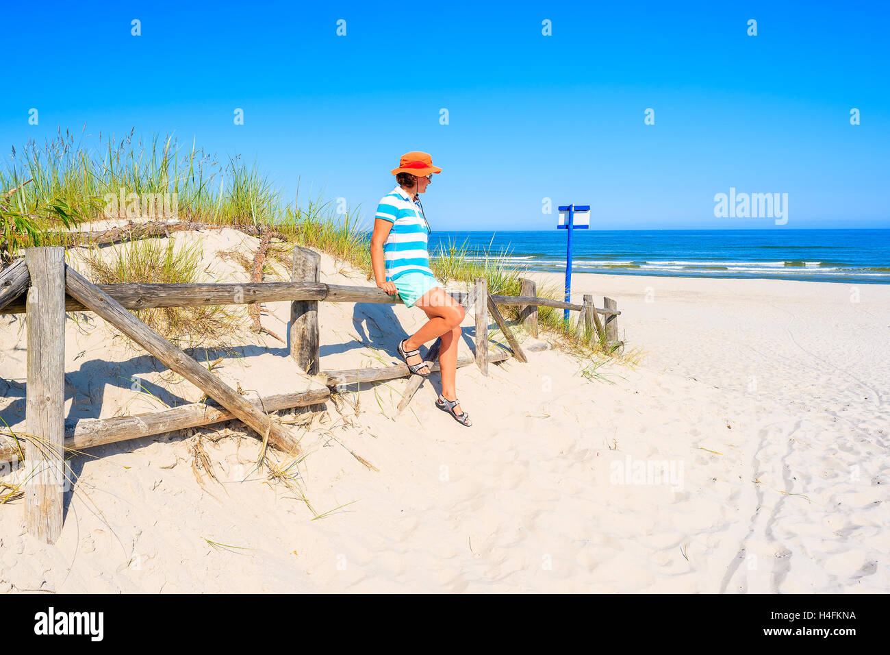 Young woman tourist standing at entrance to beautiful sandy beach in Lubiatowo coastal village, Baltic Sea, Poland Stock Photo