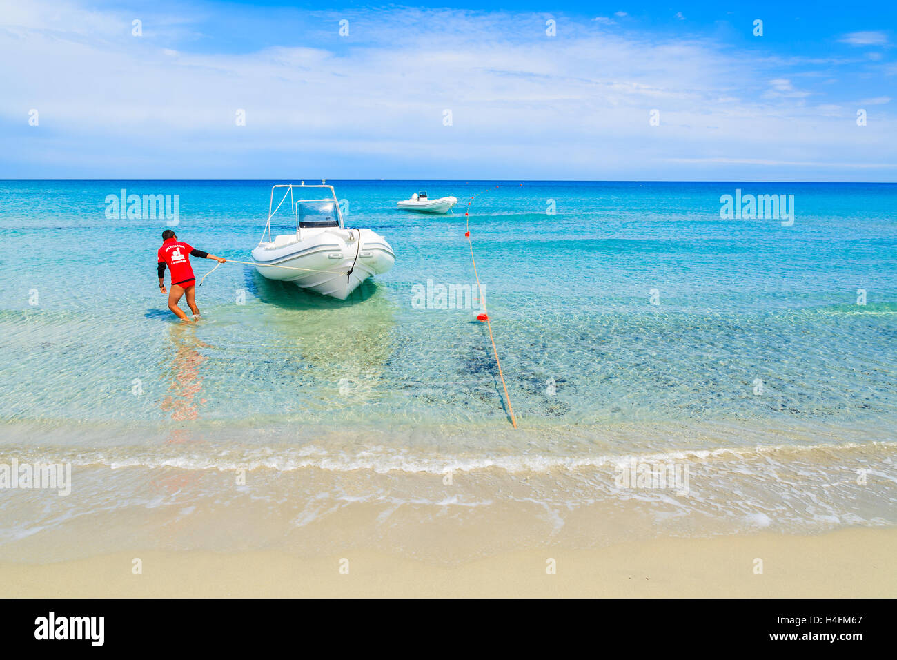 PORTO GIUNCO BEACH, SARDINIA - MAY 28, 2014: lifeguard pulling a rescue boat to shore on Villasimius beach, Sardinia island, Italy. This area is very popular destination for water sport activities. Stock Photo