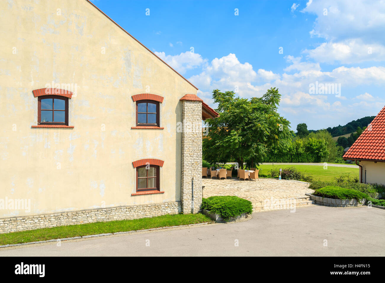 Historic building with chairs and tables on sunny terrace in Paczultowice village, Poland Stock Photo
