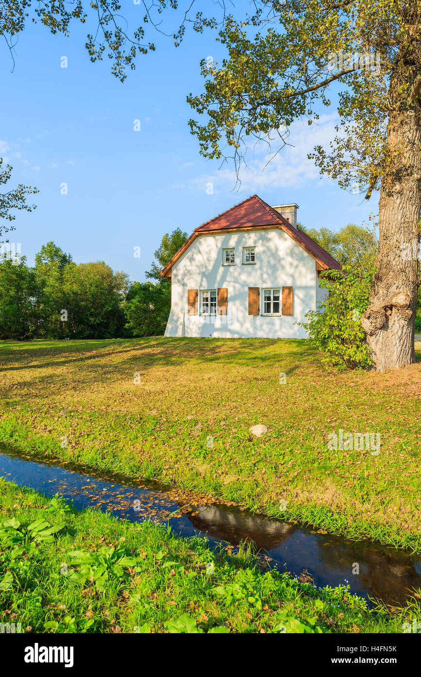 Traditional cottage house and small river in countryside landscape, Radziejowice village, Poland Stock Photo