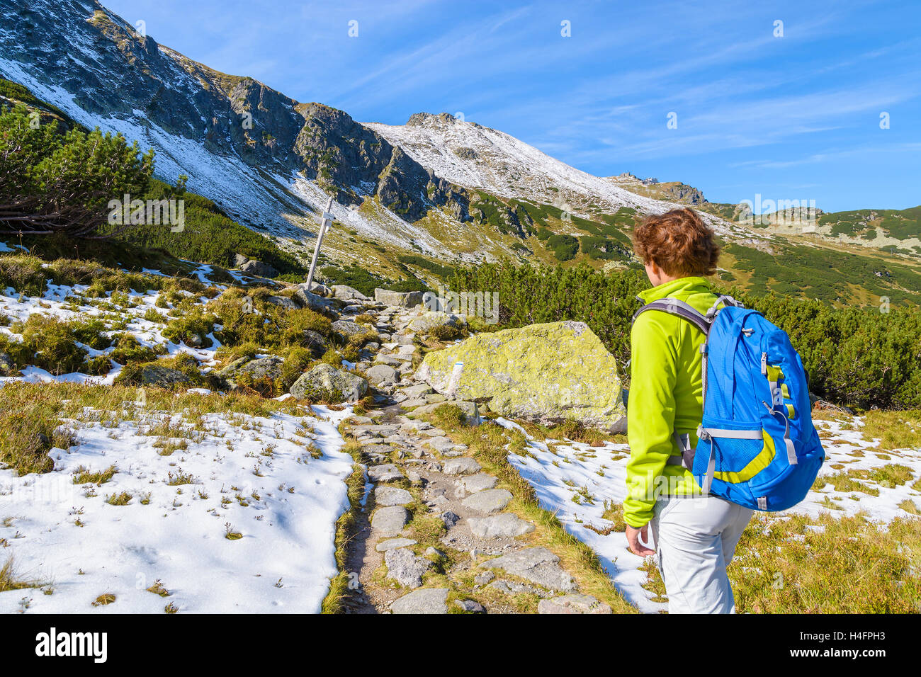 Young woman backpacker on mountain trail in Gasienicowa valley in autumn season, High Tatras, Poland Stock Photo
